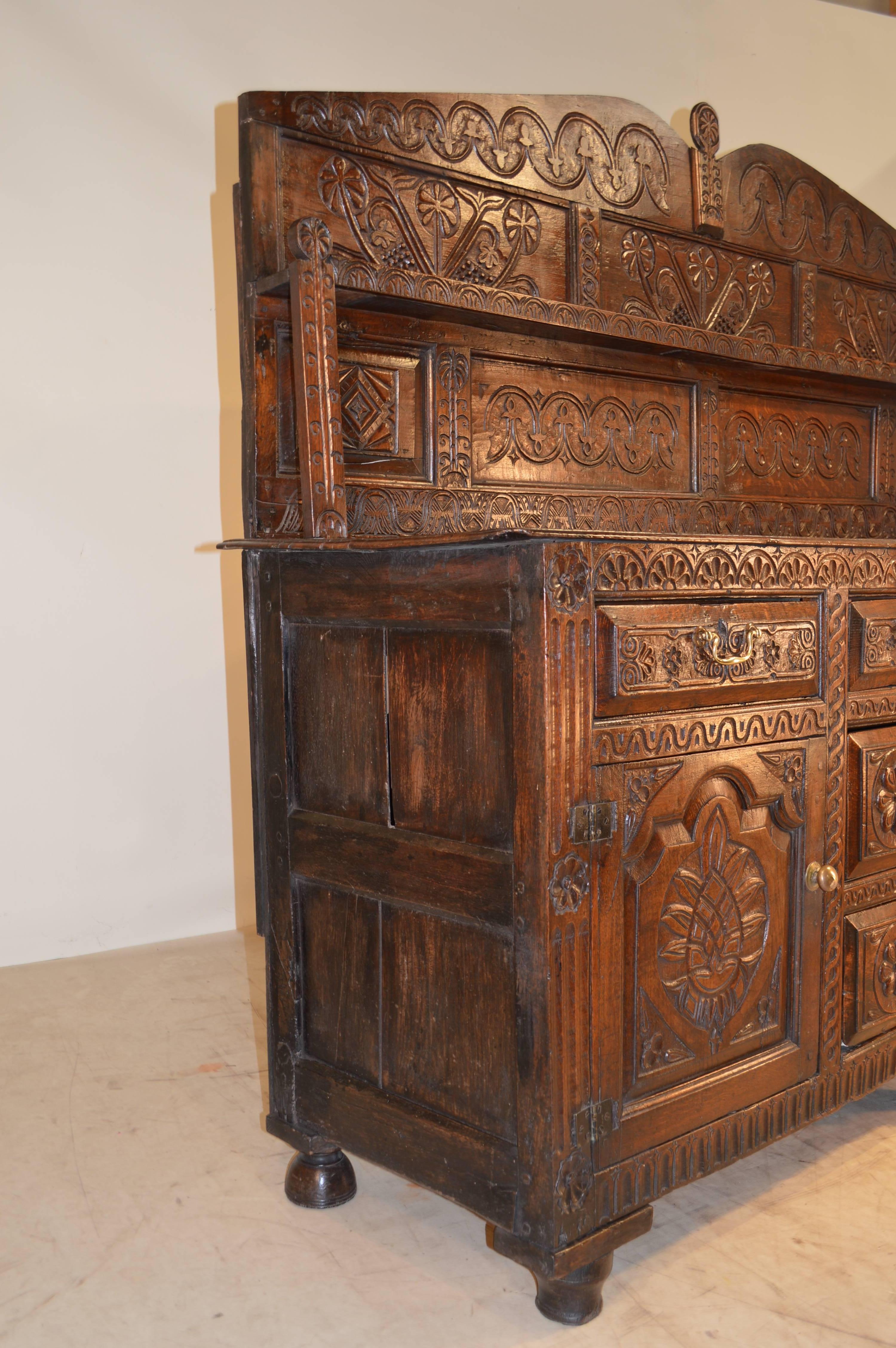17th century William and Mary dresser. The backsplash is panelled and carved and has a single plate shelf that is supported by two splats, which are also carved. The top is made up of planks, and follows down to a dresser base with panelled sides