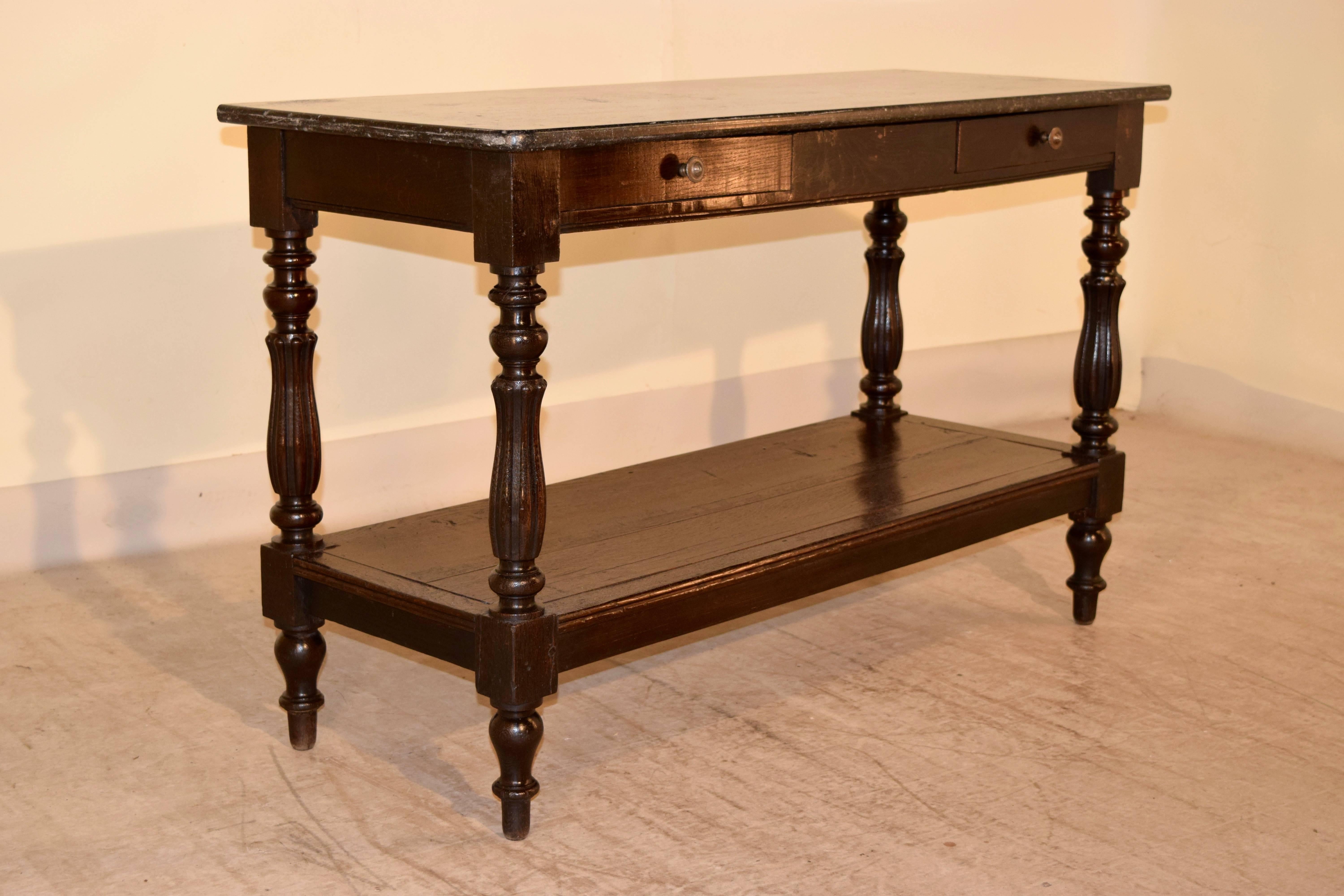 19th century English serving table made from elm with a marble top following down to two drawers and supported on hand-turned and reeded legs, with a lower shelf and turned feet.