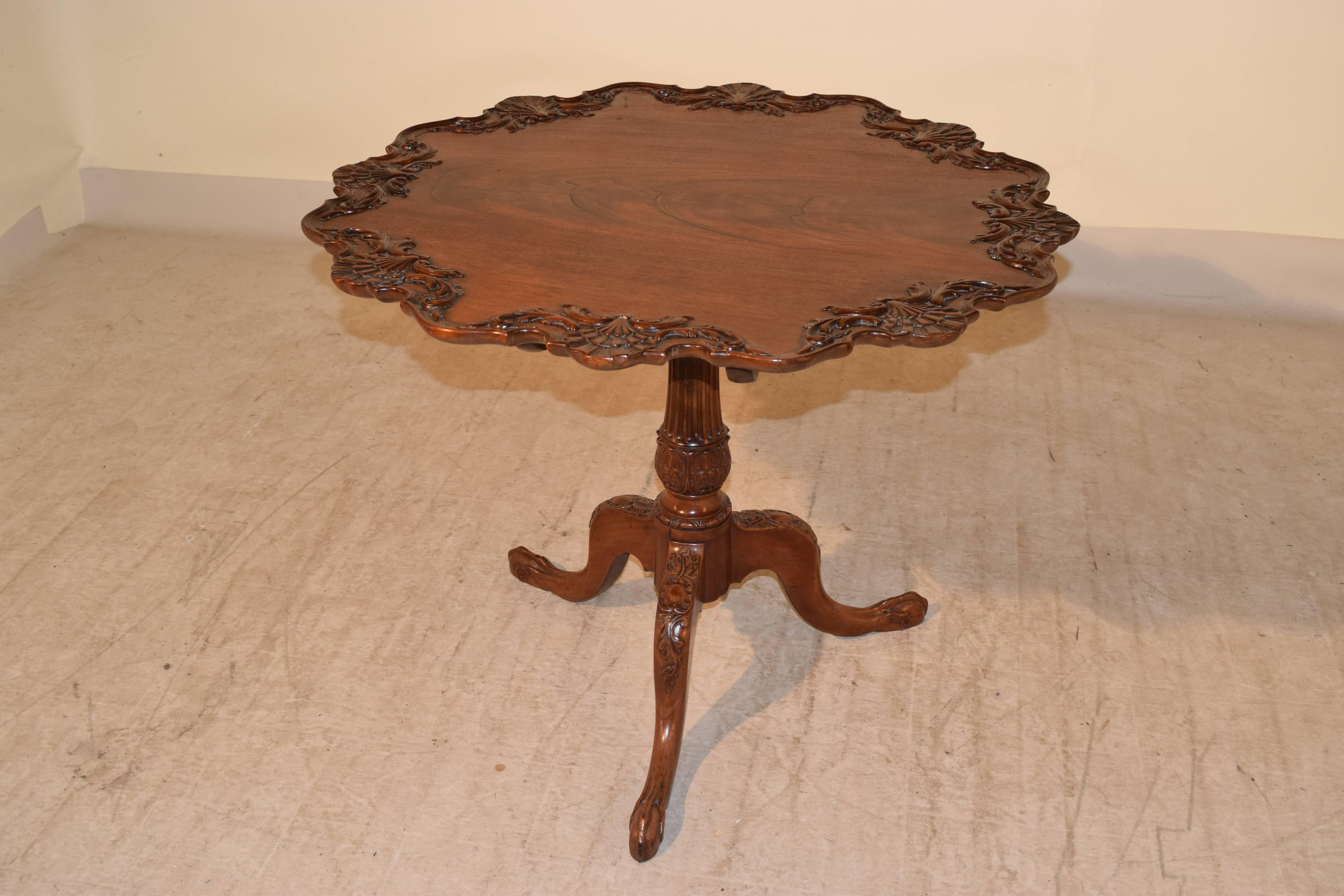 18th century Irish tea table made from mahogany. The top has a wonderfully scalloped and hand-carved edge with shell decoration. The top has gorgeous figured wood as well. The base is a birdcage on a turned and carved pedestal, supported on three
