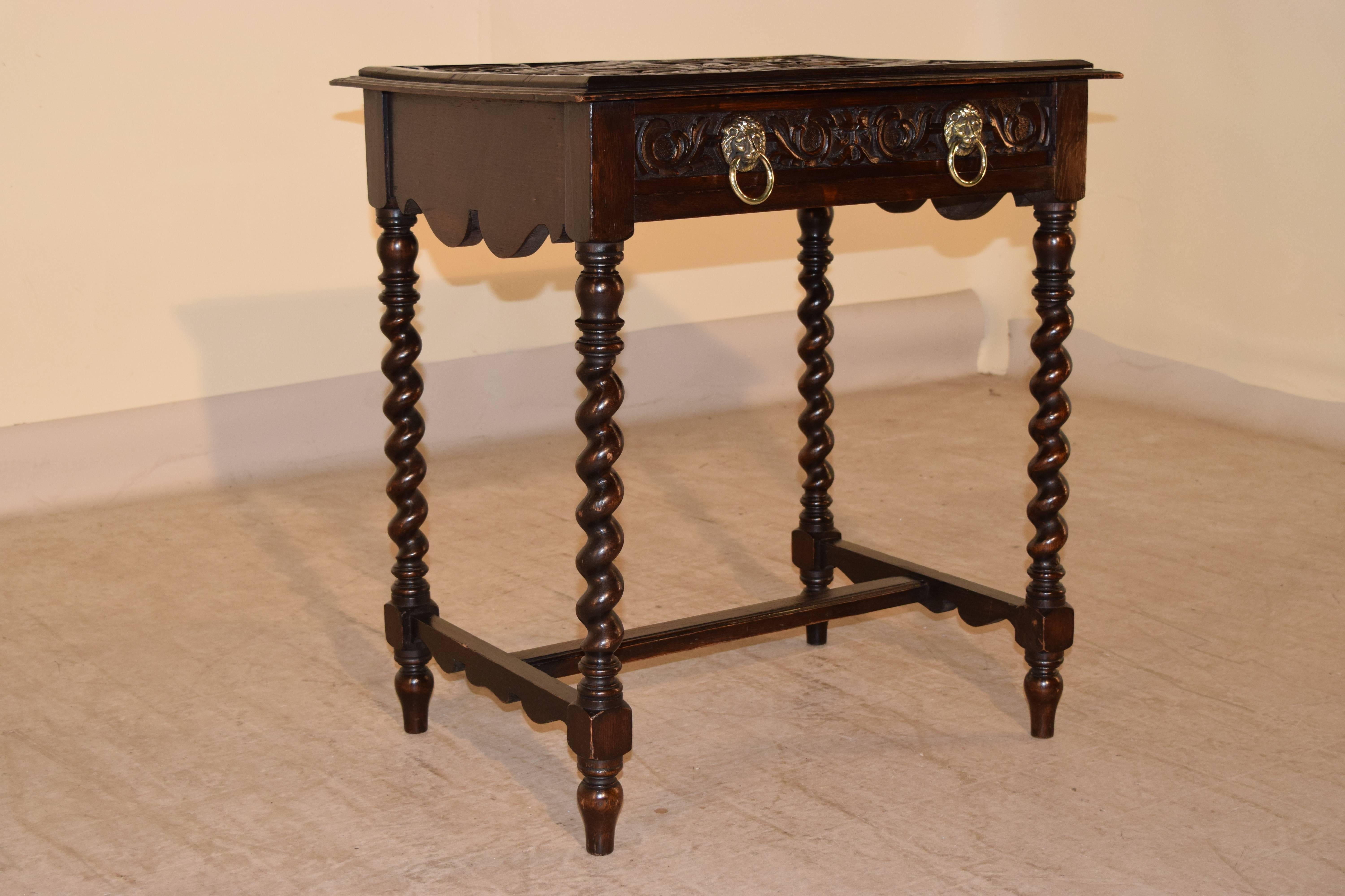 19th century, English side table made from oak. The top is heavily carved and has a stepped molded edge. There is a single drawer with a carved drawer front with lion ring pulls and scalloped aprons on the sides. The legs are hand turned barely