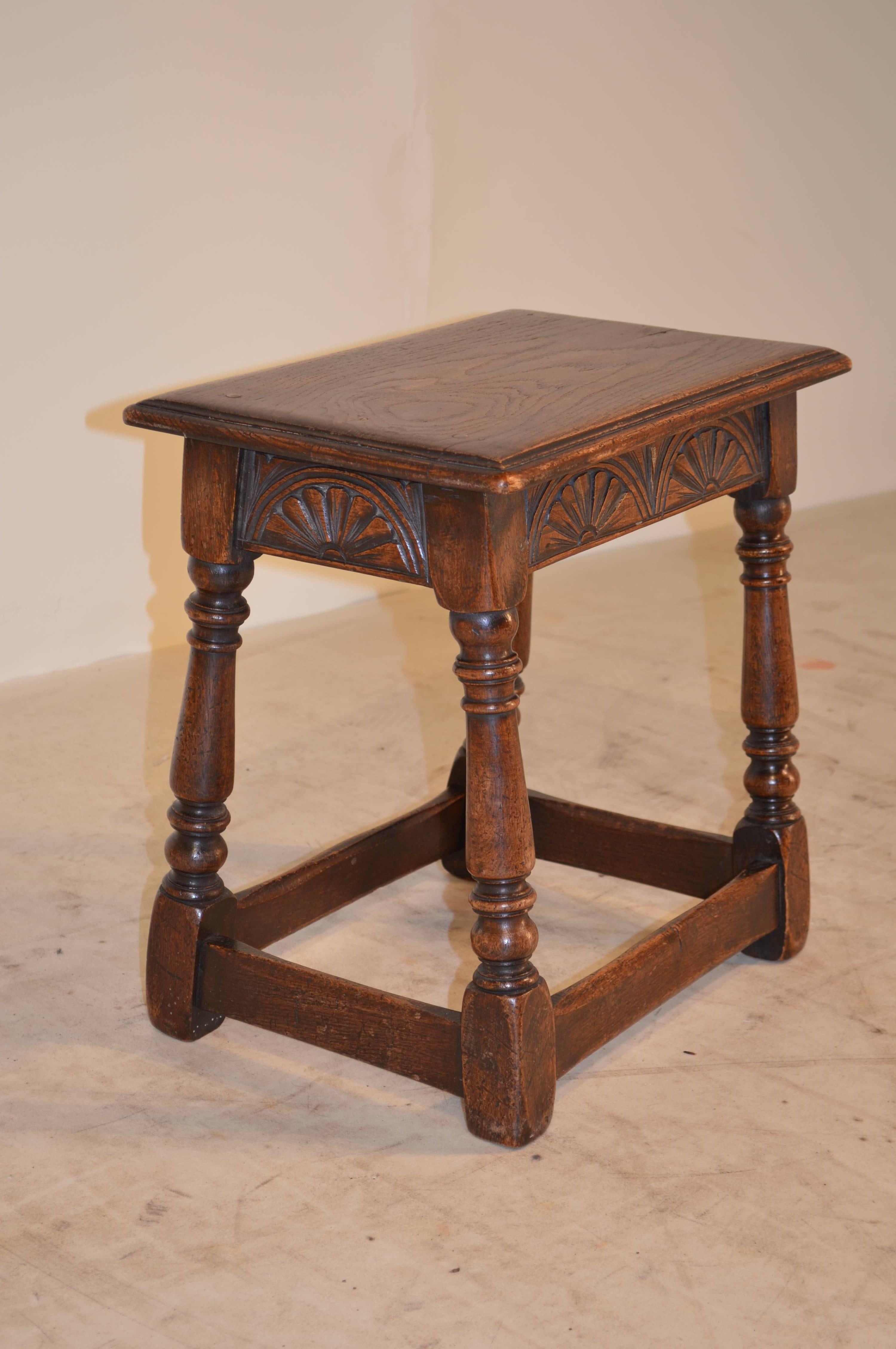 19th century English oak joint stool with carved decoration on the apron. The top is double beveled and has slight shrinkage. The legs are hand-turned and are joined by stretchers.