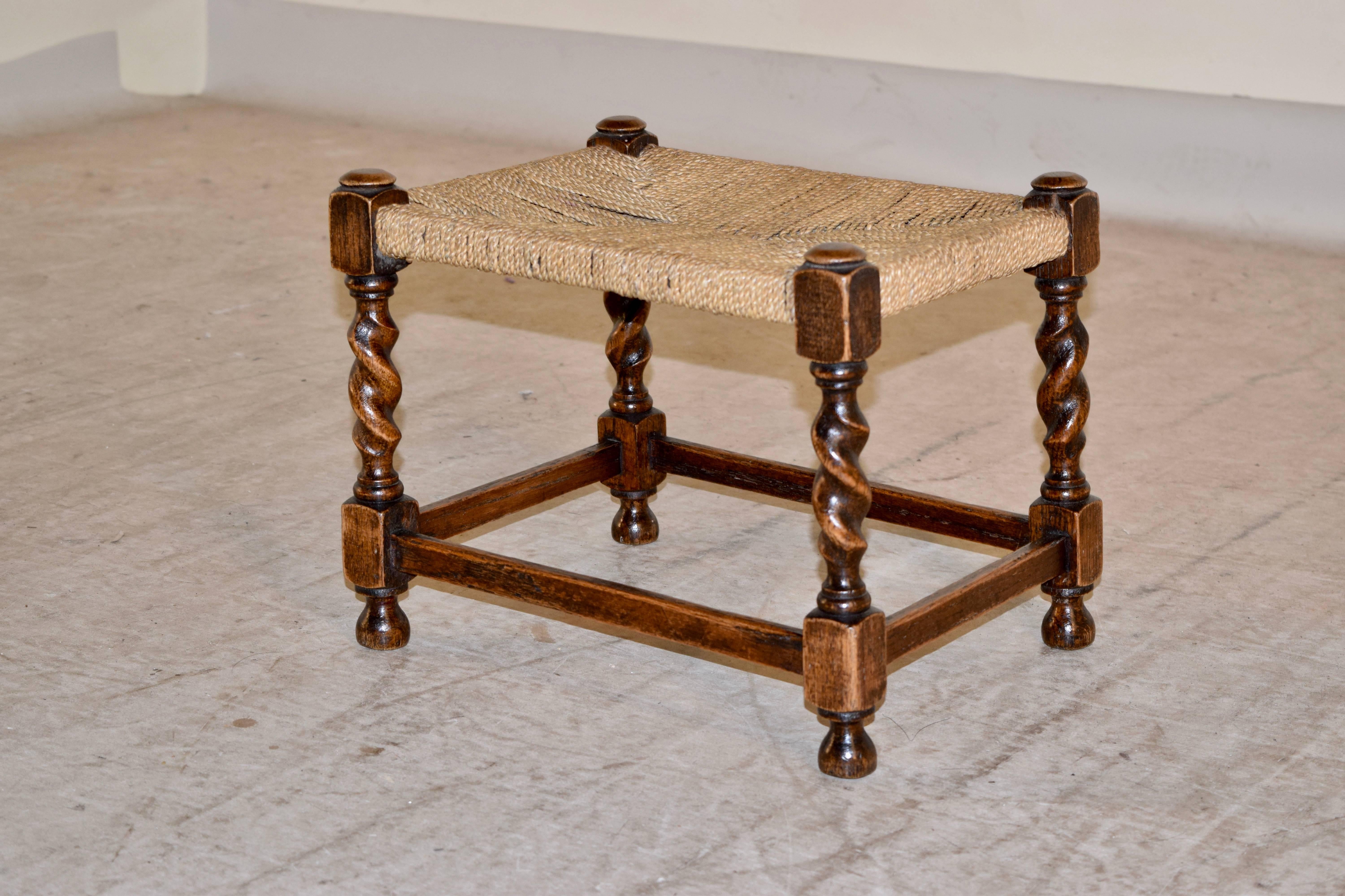 19th century small oak stool from England with a woven rush top following down to hand-turned barley twist legs, joined by simple stretchers and raised on turned feet.