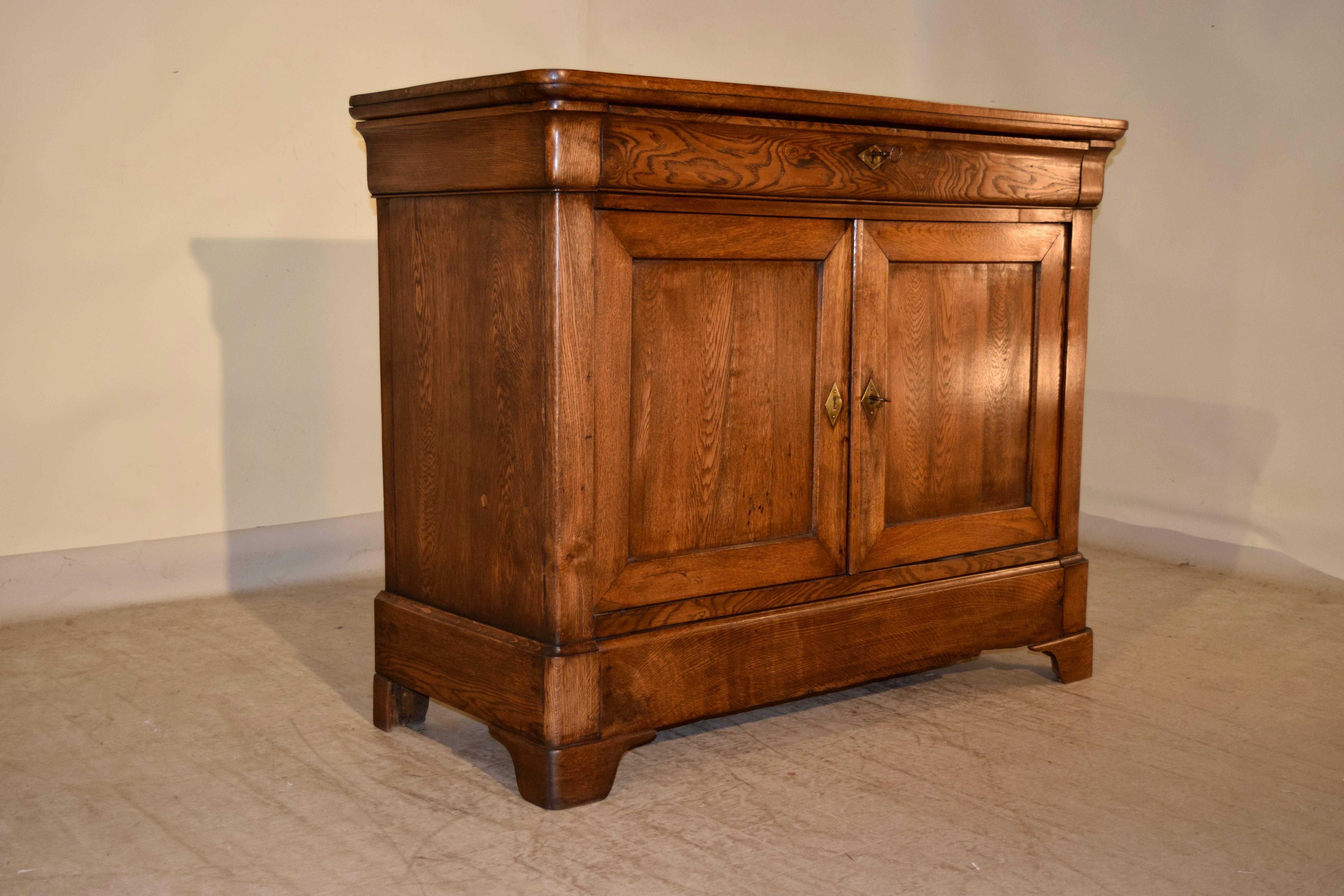 19th century Louis Philippe buffet from France made from oak and elm. The top is nicely grained and follows down to a single drawer which has an elm drawer front, over two paneled doors which open to reveal storage. The piece has simple sides and a