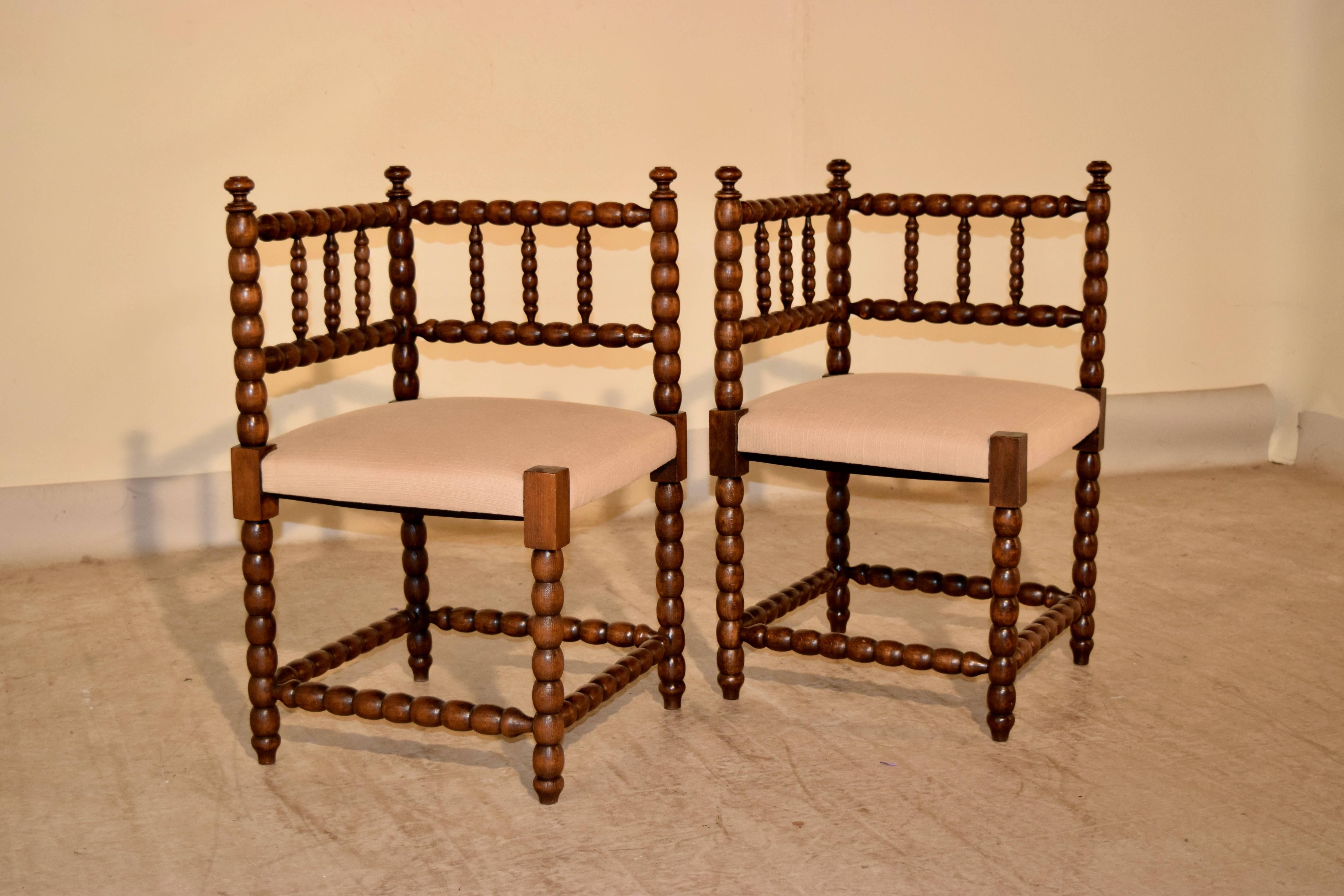 Pair of 19th-century French corner chairs made from oak. The frames are hand-turned in a spool design and the seats have been newly upholstered in linen.
  