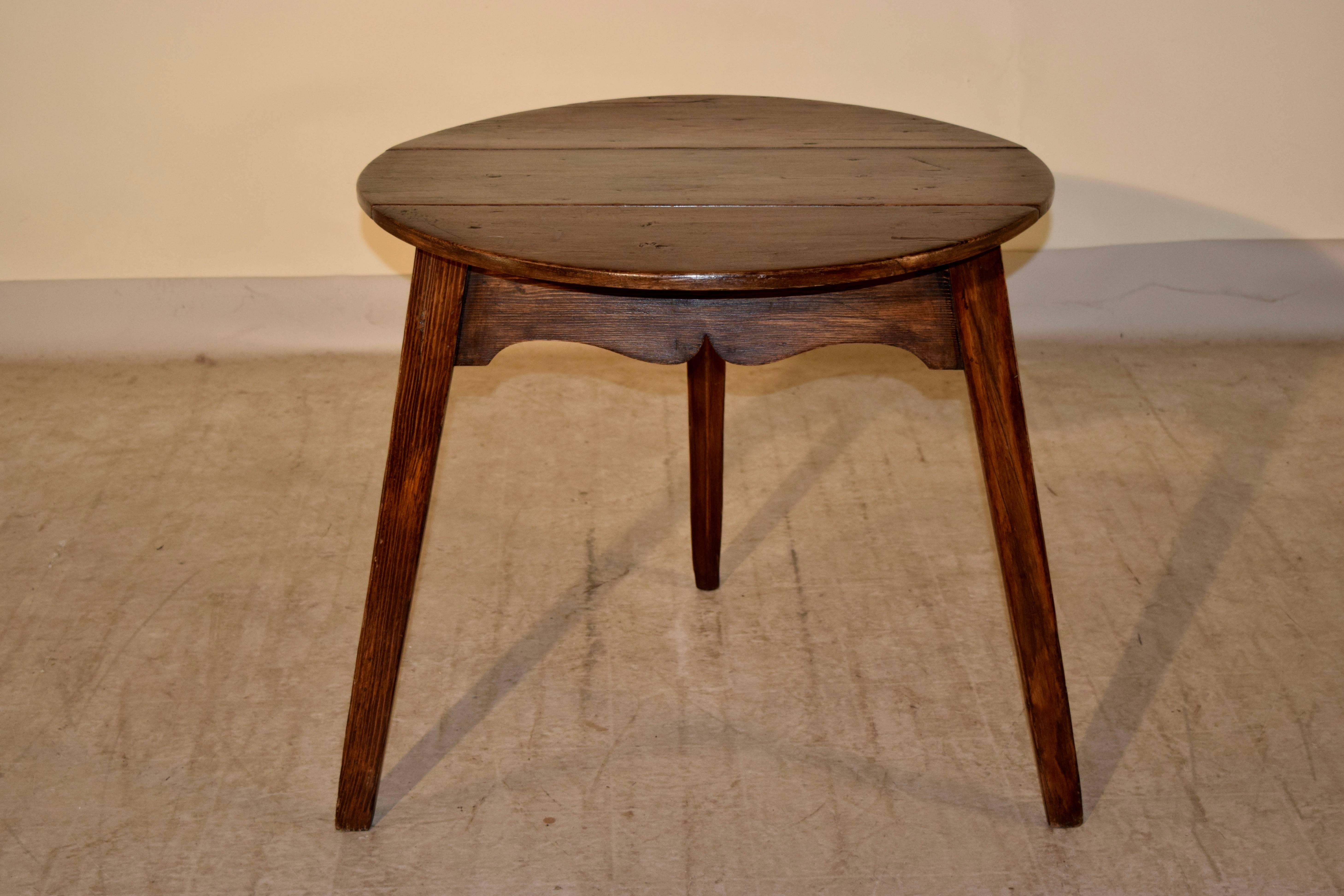 Period Georgian English pine cricket table with an unusual drop leaf front. It has a three plank top and one of the planks drops down, which we have never seen. The piece has a scalloped apron and is supported on three splayed legs.