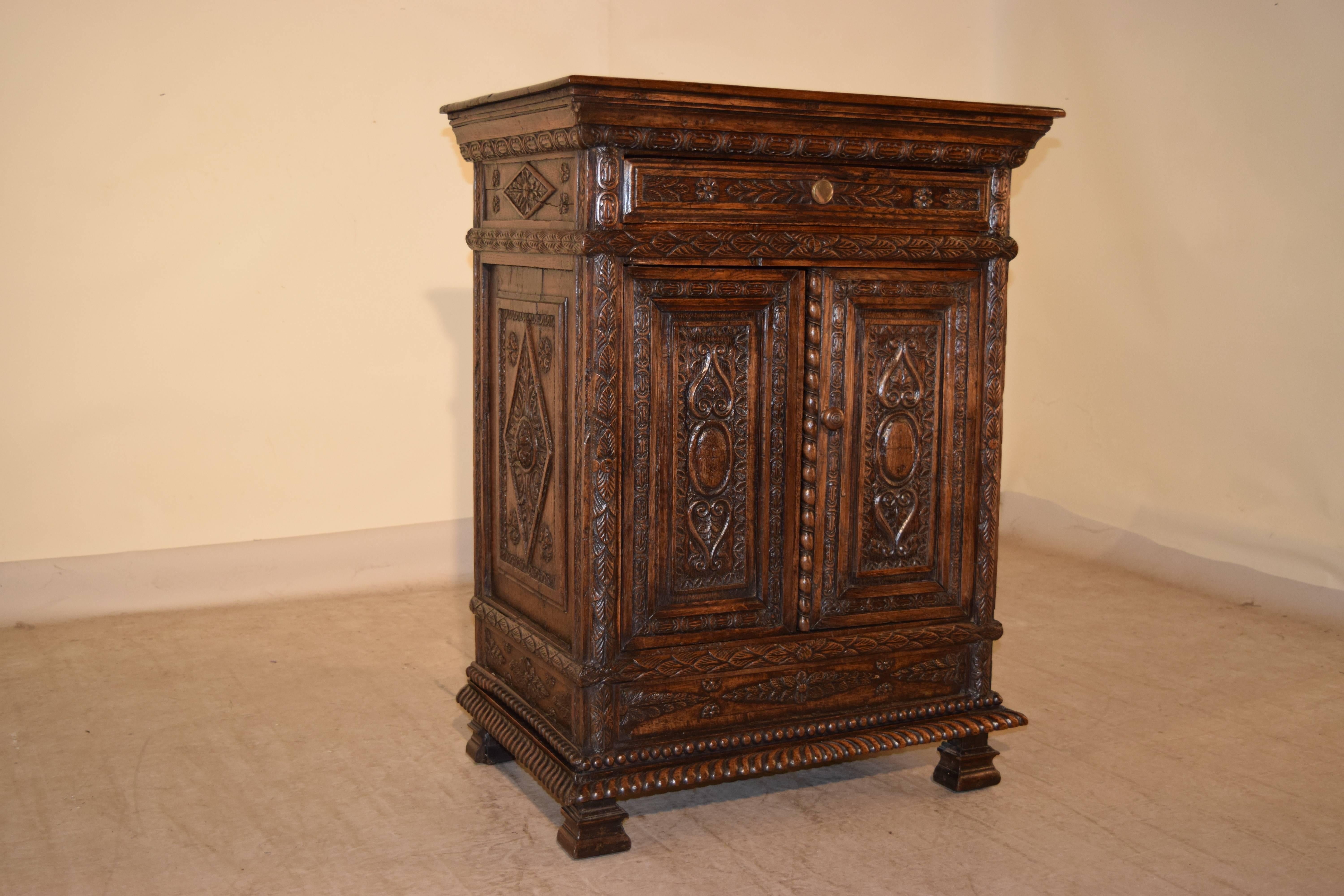 19th century carved oak cabinet from France. The top has a beveled edge, following down to a molded and carved decorated apron. There is a single drawer in the front, over two doors, which open to reveal shelving. The sides are raised and carved