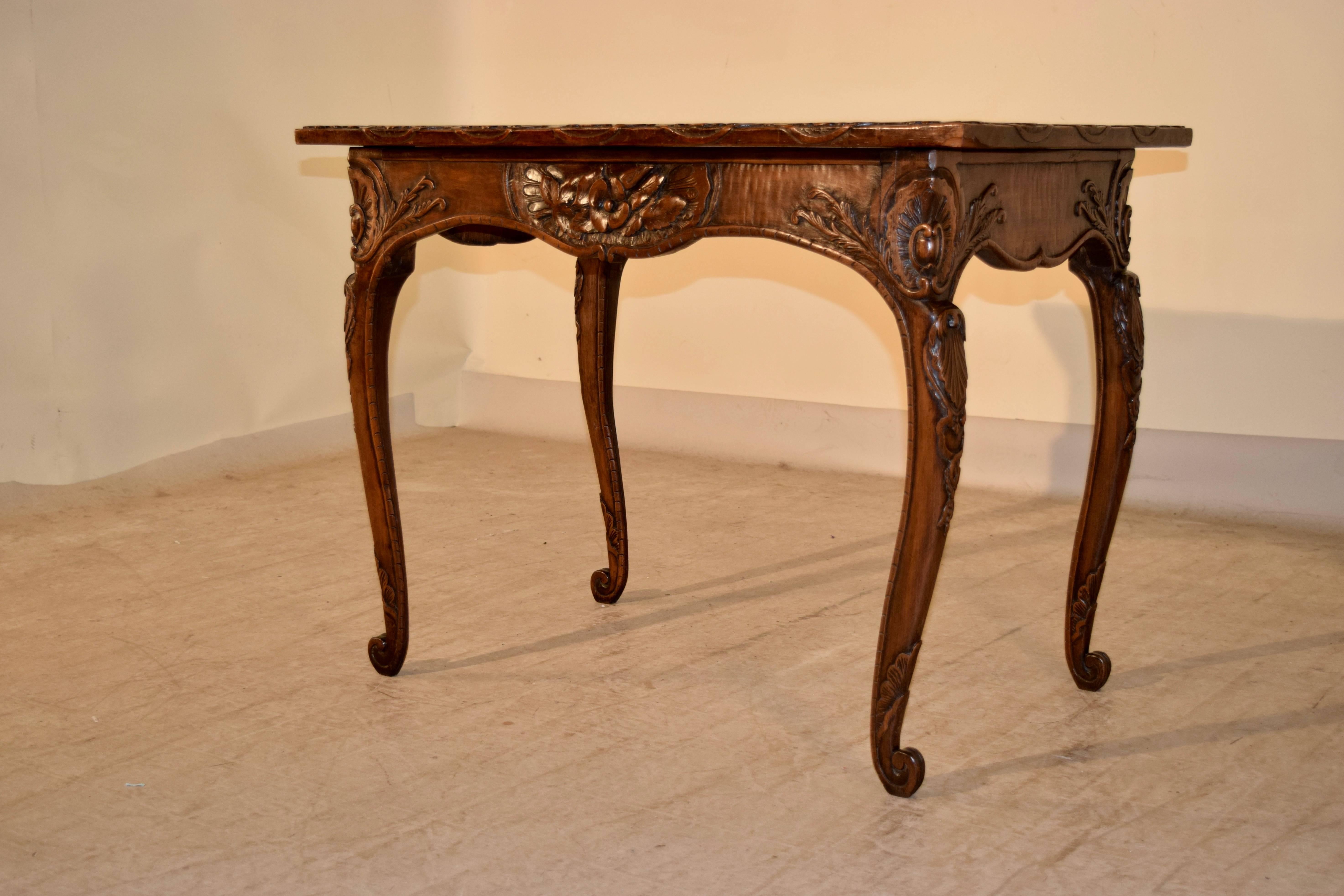 19th century Irish table made from walnut. The top is banded with exquisite carving in a shell pattern, following down to a scalloped apron, which has caved central cartouche with florals, and each corner also carved to accentuate the cabriole legs