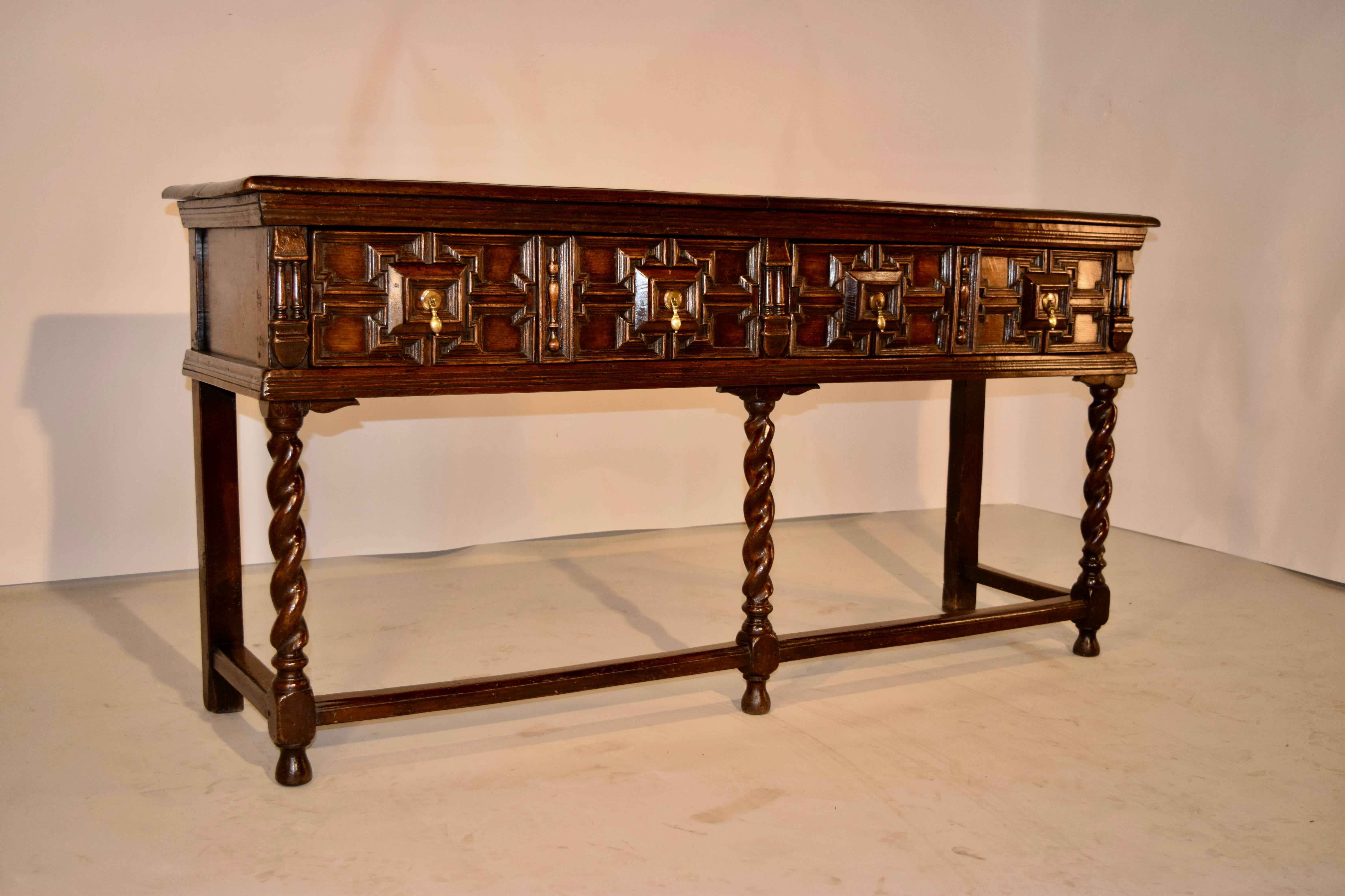 Early 19th century English oak sideboard with a two board top, which has a beveled edge and normal signs of wear. The case has paneled sides and two drawers in the front with geometric molded paneled drawer fronts. The front legs are hand-turned