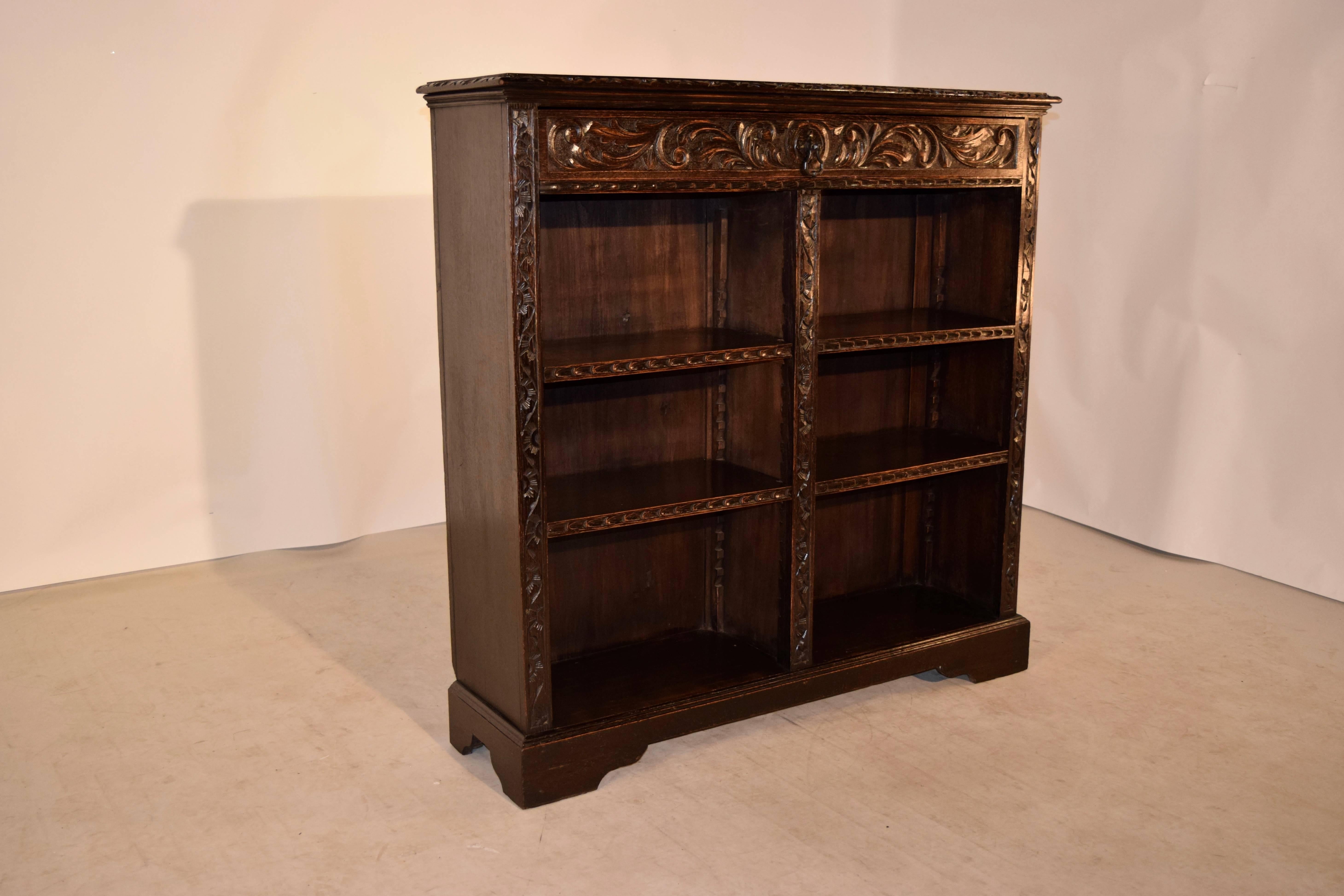 19th century English oak bookcase with a bevelled and gadrroned edge around the top, following down to a single drawer at the top, over four adjustable shelves, all with hand-carved front edges. The case has matching carving on the side and centre
