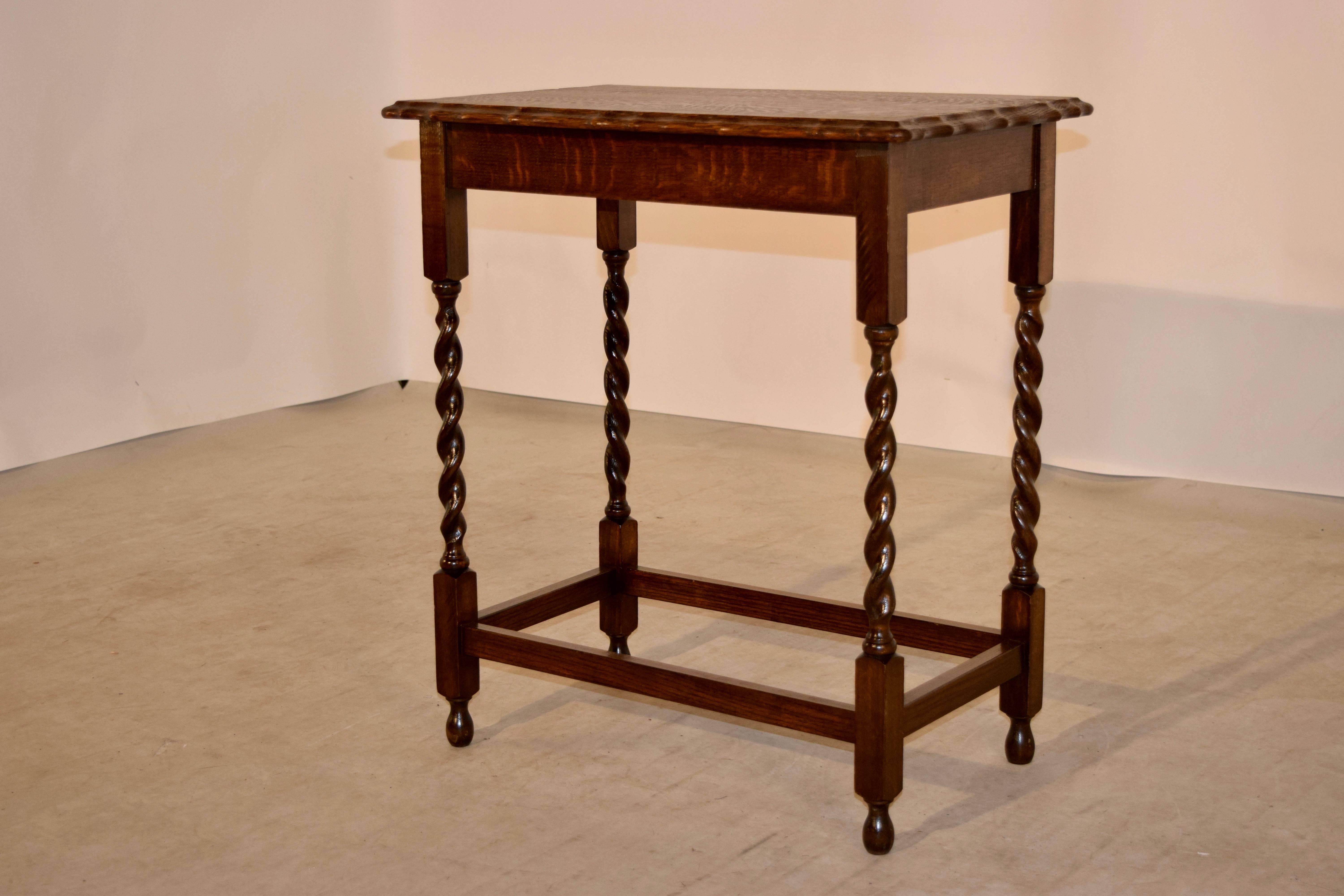 English oak side table with a rectangular shaped top which has a double beveled and scalloped edge following down to a simple apron and hand-turned barley twist legs, joined by simple stretchers. Raised on hand-turned feet.