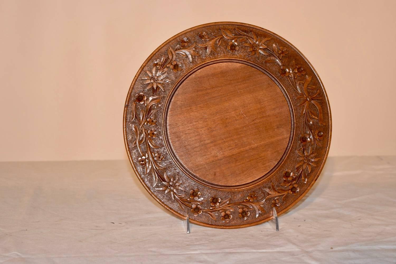 19th century Swiss bread board made from fruitwood. The front border is hand-carved with Edelweiss and flowers surrounding a central surface for cutting. The back is hand-turned.