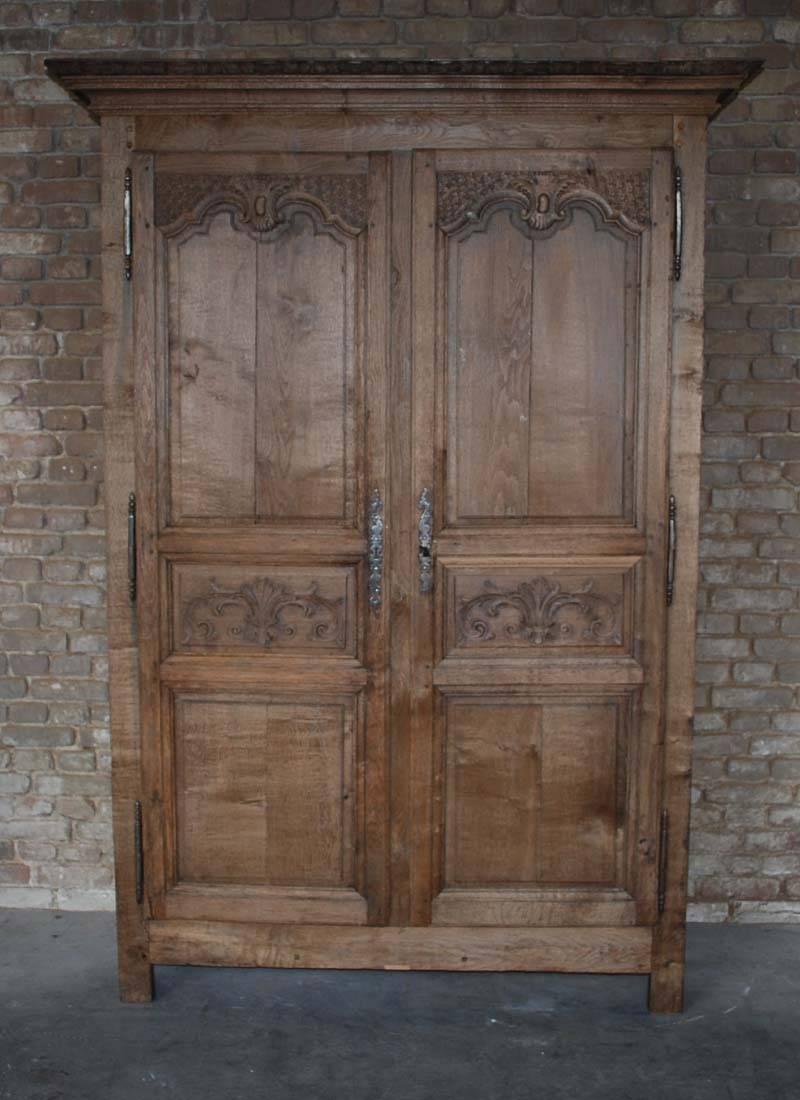 An early 19th century oak wedding cabinet or Armoire from northern France.
recessed panel sides, beautifull carved ornaments on the doors and moulding at the top.
Original hardware. Cleaned surface, bare wood soft matted finish.
