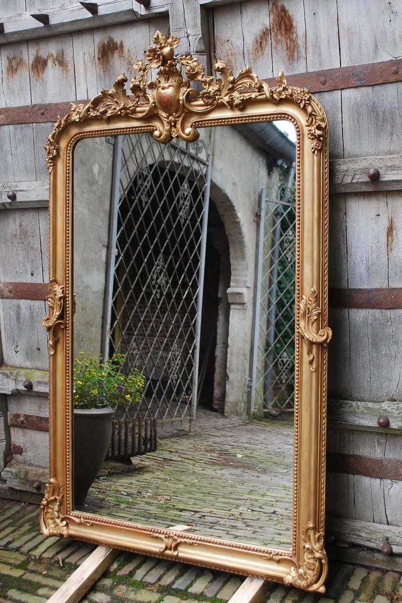 A beautiful large antique French Louis Philippe mirror with detailed crest. The detailed crest depicts the classical stylized acanthus leaves, flowers, and leaves. The ornaments are repeated halfway and at the bottom section.  There is a nice pearl