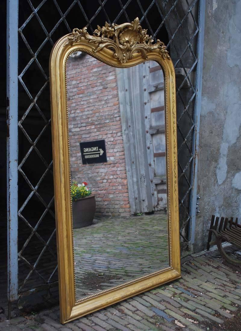 Extraordinary large antique French Louis Philippe mirror with a beautifully detailed cartouche. The mirror frame is largely gold leaf gilt and the gold color is very strong and intact after all these years. The gold leaf is partially polished to