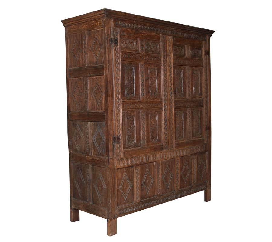 Very early 17th century cabinet or wardrobe made from oakwood.
The cabinet is decorated with primitve jacobean carvings. 
Most likely the cabinet stood in a corner of a room, because on the right side it has no carving.
The cabinet has a light wax