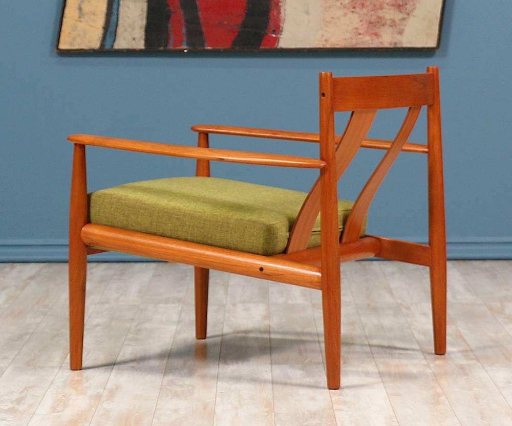 Elegant lounge chair designed by one of the few female Mid Century furniture designers, Grete Jalk, in Denmark for France & Søn c. 1960’s. Constructed of teak wood and recently reupholstered with a quality tweed fabric, two curved slats adorn the