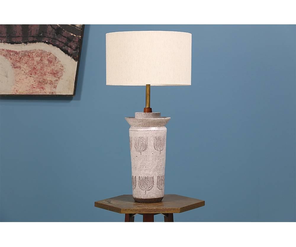 Mid-Century Modern ceramic lamp designed by Italian pottery maker, Aldo Londi for Bitossi in the 1950’s. This beautiful sculptural ceramic table lamp features a small walnut detail that contrasts beautifully with the incised details on the body.