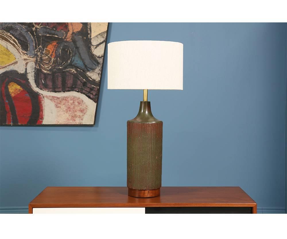 Ceramic table lamp designed by David Cressey for Architectural Pottery in the United States in the 1960’s. The rich walnut base wonderfully compliments the olive-green ceramic with texture that accentuates the overall design. This lamp features a