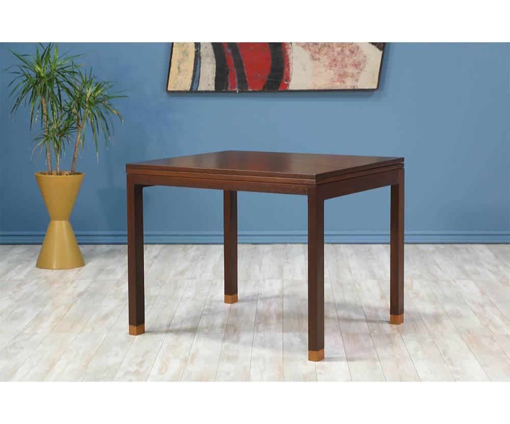 Mid Century Modern flip-top game table designed by Edward J. Wormley for Dunbar in the United States circa 1950’s. This table features a top that flips open to make a larger surface, allowing more chairs for seating. Underneath the top is a shallow