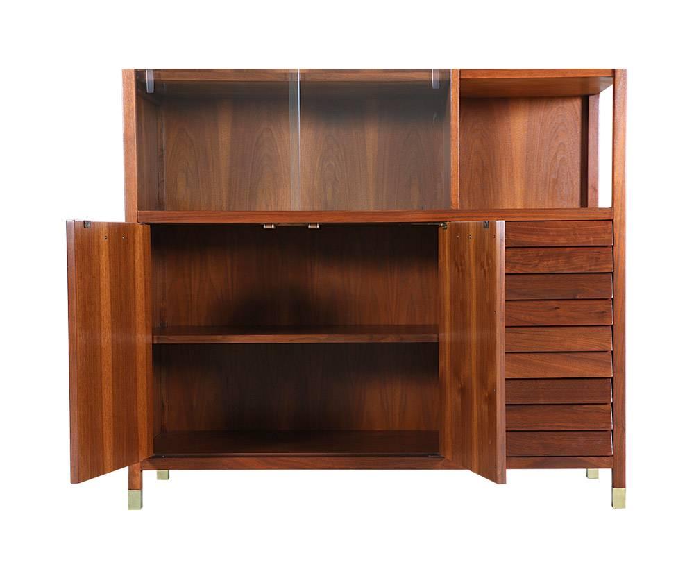 Designer: Merton Gershun
Manufacturer: American of Martinsville
Period/Style: Mid-Century Modern
Country: United States
Date: 1960s

Dimensions: 57.57 H x 50 W x 18 D
Materials: Walnut wood, brass hardware, glass doors
Condition: Excellent,