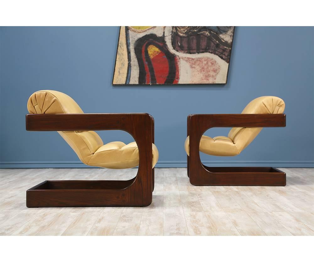 A pair of Lounge Chairs designed by Lou Hodges for California Design Group in the United States circa 1970’s. This set is comprised of a walnut-stained oak wood frame that supports the newly upholstered seats in tan leather and new foam interior.