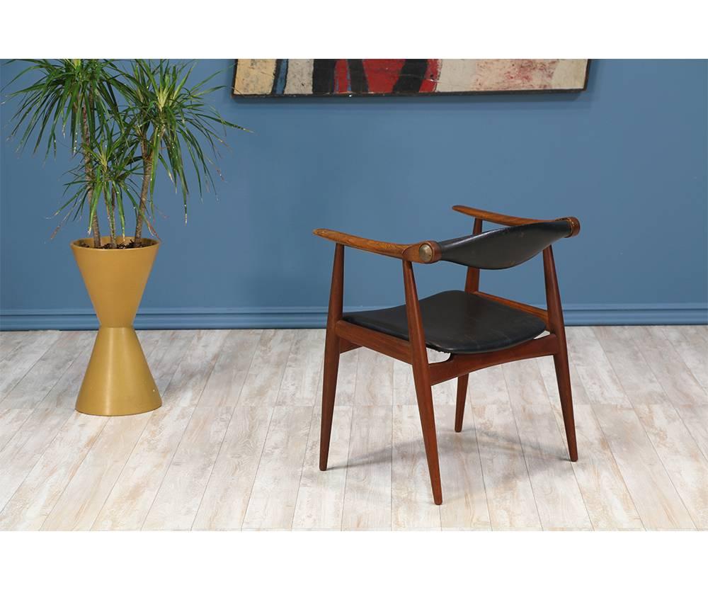 Iconic armchair designed by Hans J. Wegner for Carl Hansen & Søn in Denmark c. 1960’s. The CH-34 chair features a solid teak frame with tapered legs, bull-horn style arms, and a rotating back rest that provides comfort when seated. This chair