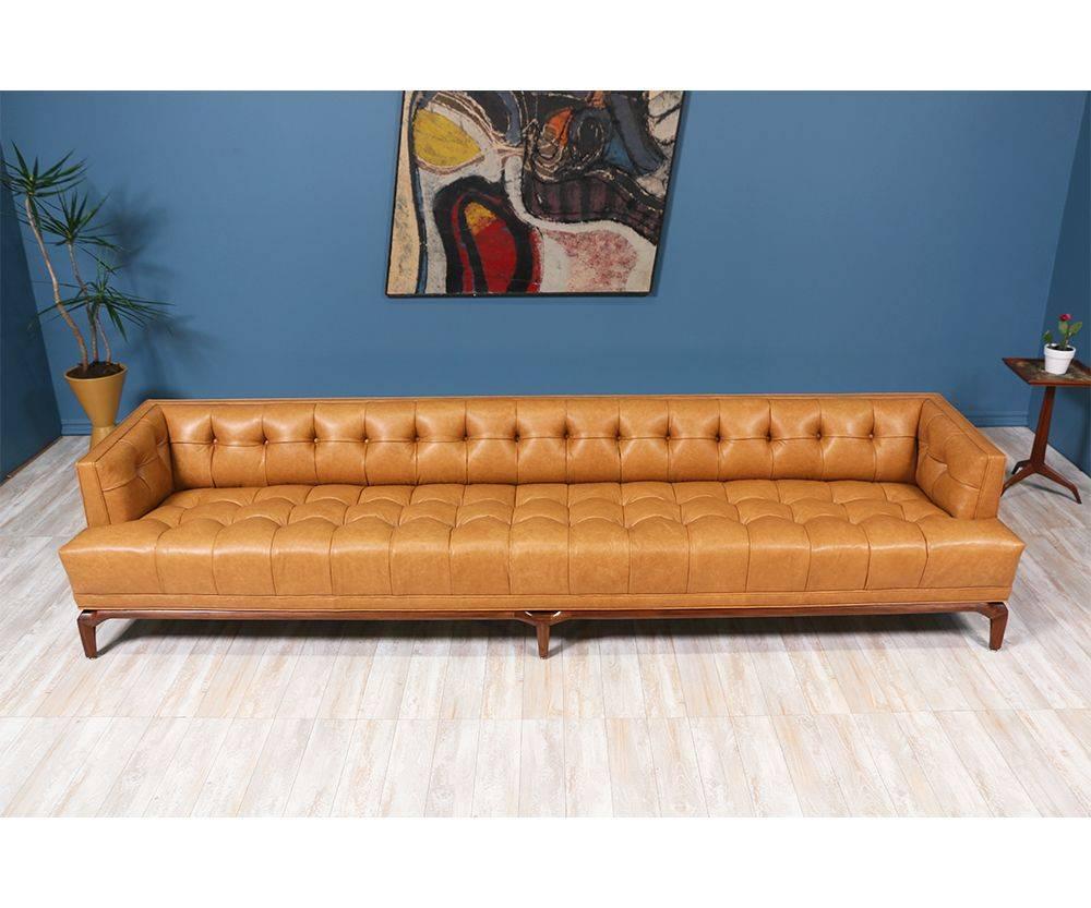 Spectacular biscuit tufted leather sofa designed by Maurice Bailey for Monteverdi-Young of Beverly Hills in the 1960’s. This 10-foot comfortable sofa is newly reupholstered in a full grain leather and set on a carved solid walnut wood base. Designed