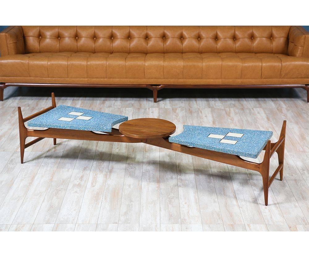 Elegant Mid-Century Modern coffee table designed and manufactured by American designer Harvey Probber in the 1950’s. Its four walnut wood legs support the blue terrazzo tile on top giving it a floating appearance. With alluring and subtle brass