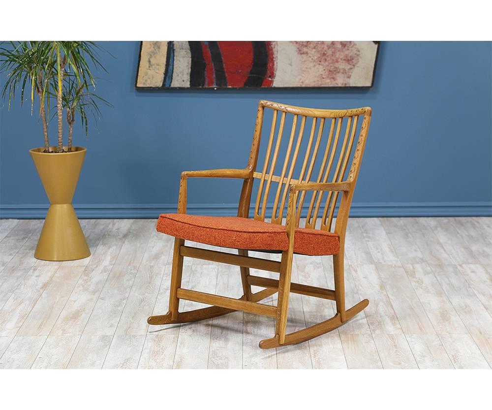 Rocking chair designed by Danish design pioneer, Hans J. Wegner, for Mikael Laursen in Denmark circa 1940. This Danish Modern iconic design is comprised of solid oak with a stunning floral ornamentation on the edges of the frame. Features an