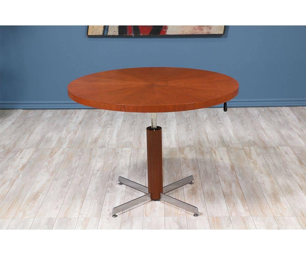 Danish Modern adjustable table designed and manufactured in Denmark in the 1950’s.  Stunning teak table top features an intricate grain pattern and sits on an adjustable steel base. This newly refinished table can be adjusted to serve as a coffee