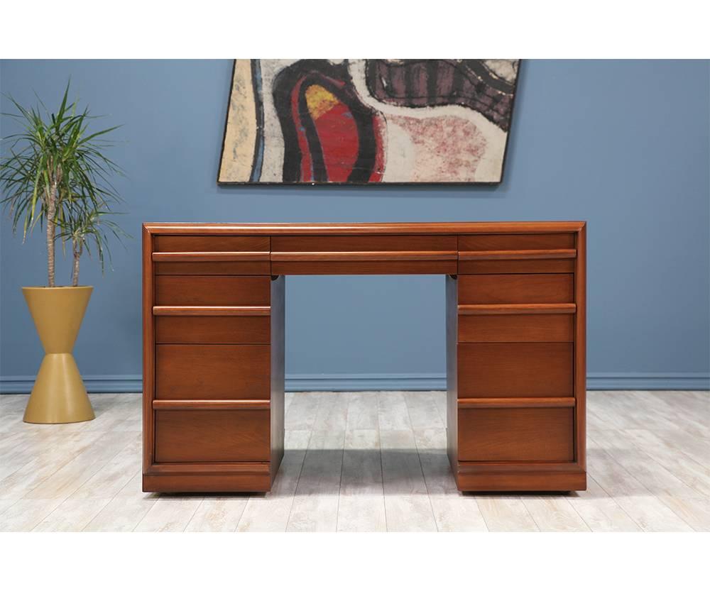 Mid-Century Modern desk designed by T.H. Robsjohn Gibbings for Widdicomb in the United States circa 1960’s.  Crafted with walnut wood, this desk features six dovetailed drawers on each side with ample space and a center drawer. The larger bottom