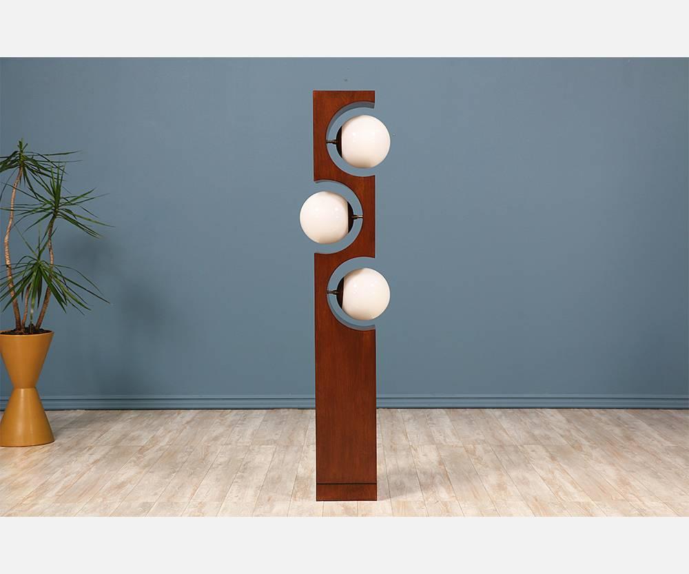 Mid-Century floor lamp designed and manufactured by Modeline of California in the United States circa 1960. The dramatic curves of the rectangular walnut body give space to three new globe bulbs held up by subtle brass hardware. A unique looking