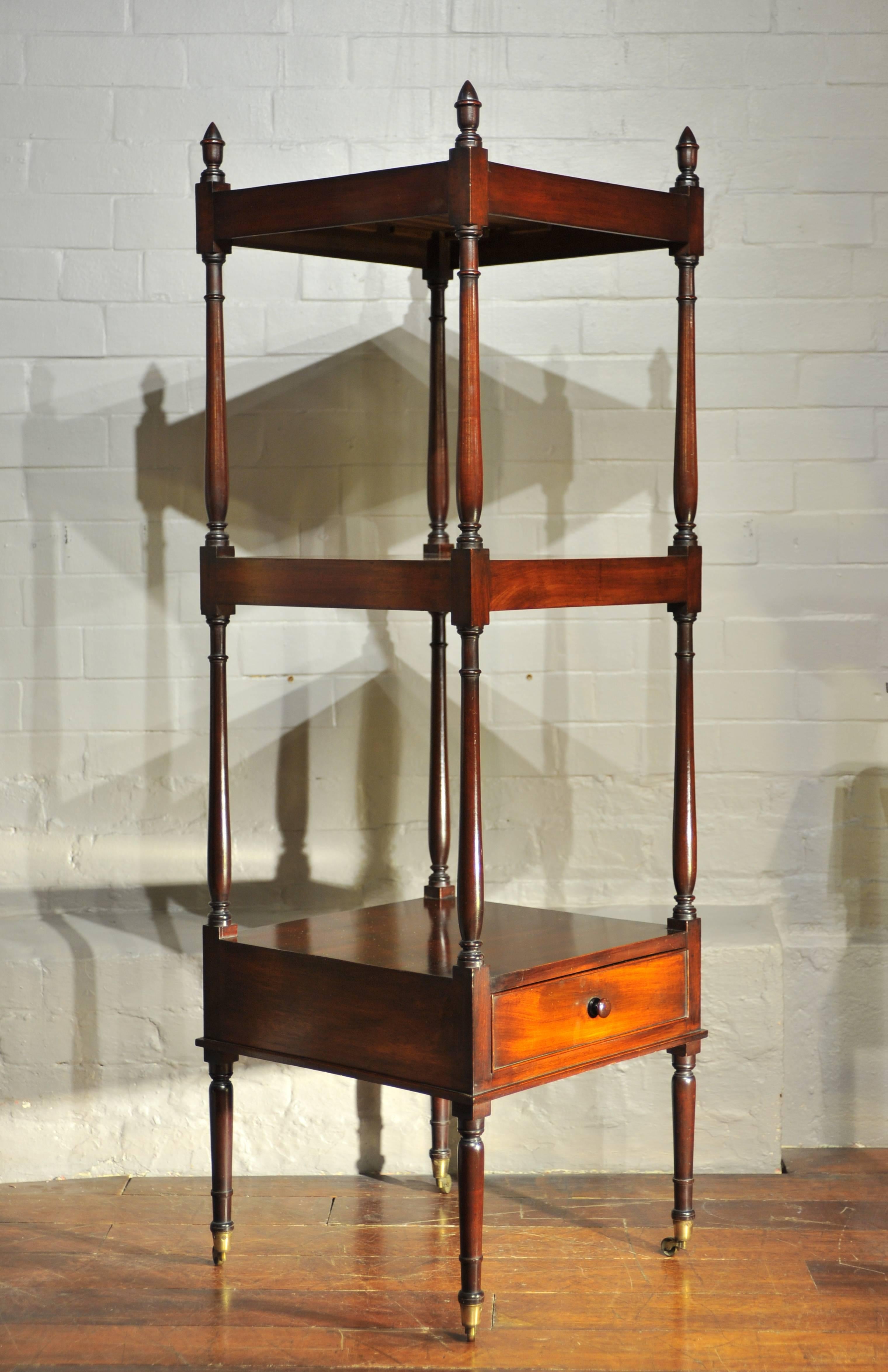 A fine and elegant Regency period mahogany whatnot. The slender turned and balluster shaped supports terminating with finials to the top and brass castors to the legs; the bottom tier with single drawer.