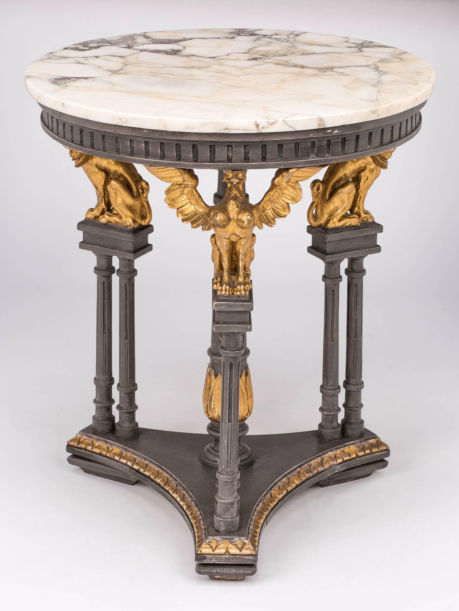 1930s, round table with original marble top. Base is triangular pedestal style, supported by beautifully wood carved three winged female Griffins. They all have lovely bosoms.