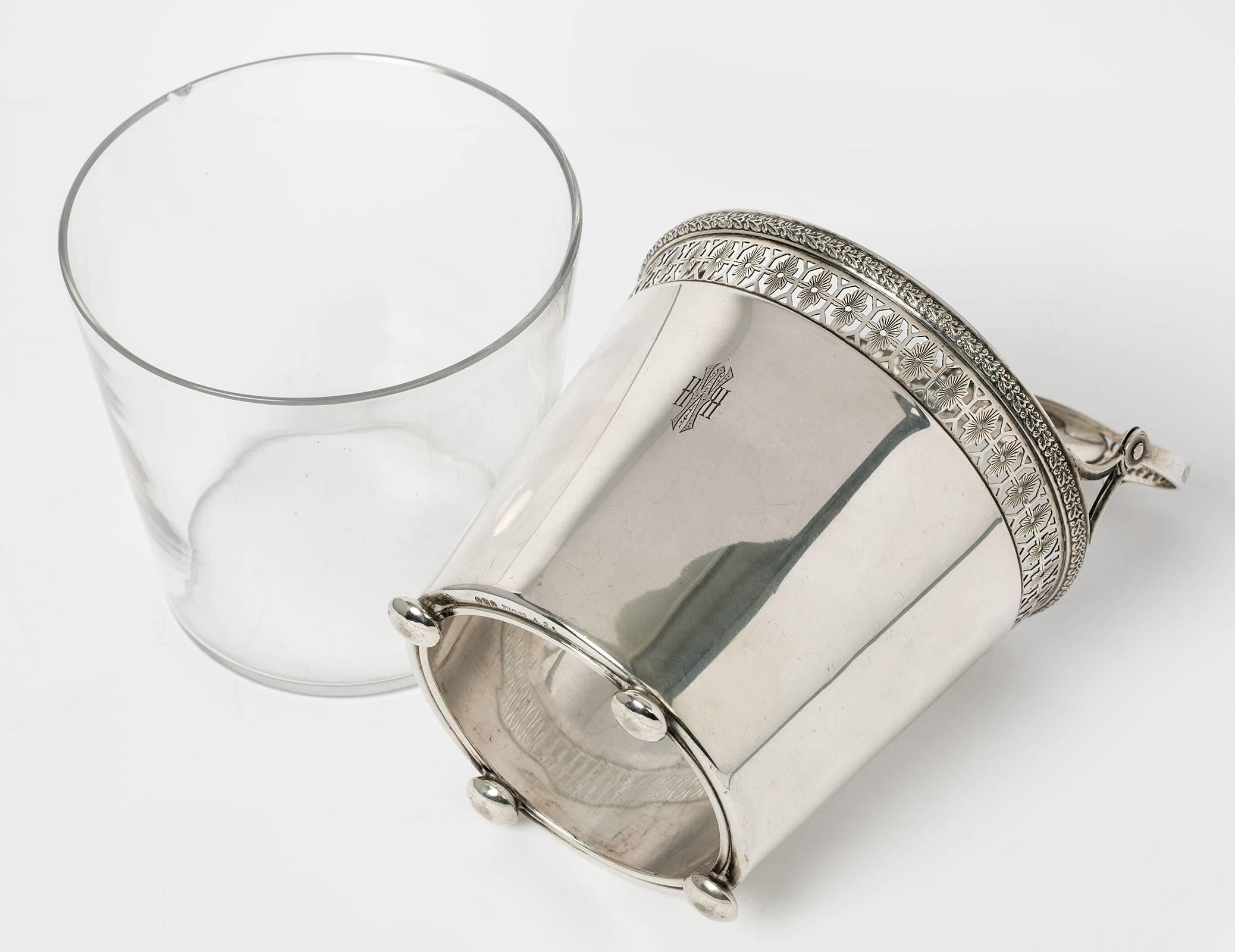 Lovely sterling silver ice bucket with glass liner and handle. Top edge is decoratively bordered with band of pierced work. Stands on small round silver feet. Monogrammed HWH.
Minor wear and dimples. Lovely used condition.
Bucket size without the