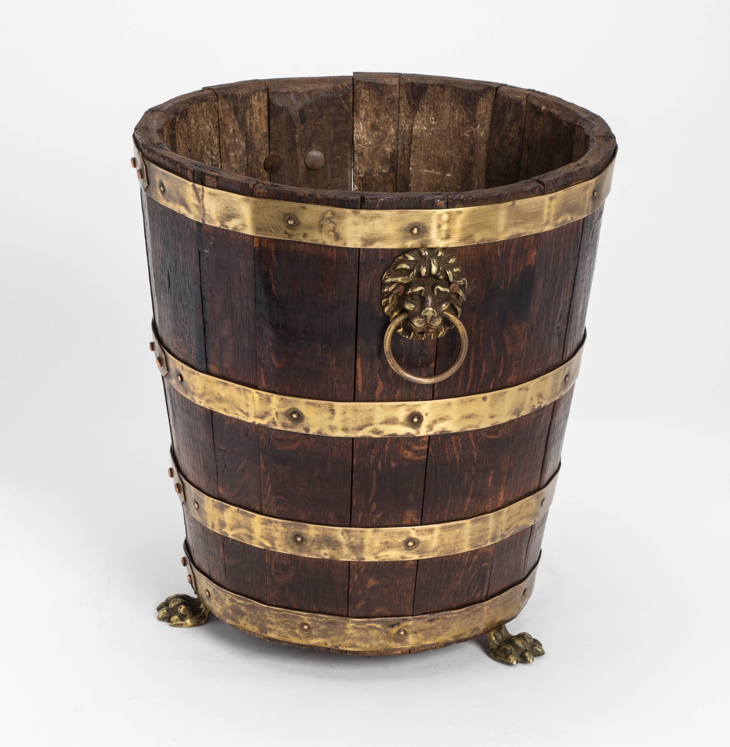 Charming wooden bucket from the George III period. Made with hard oakwood held together with brass bandings. Decorative brass lion mask handles and lion feet. A very nice old piece.