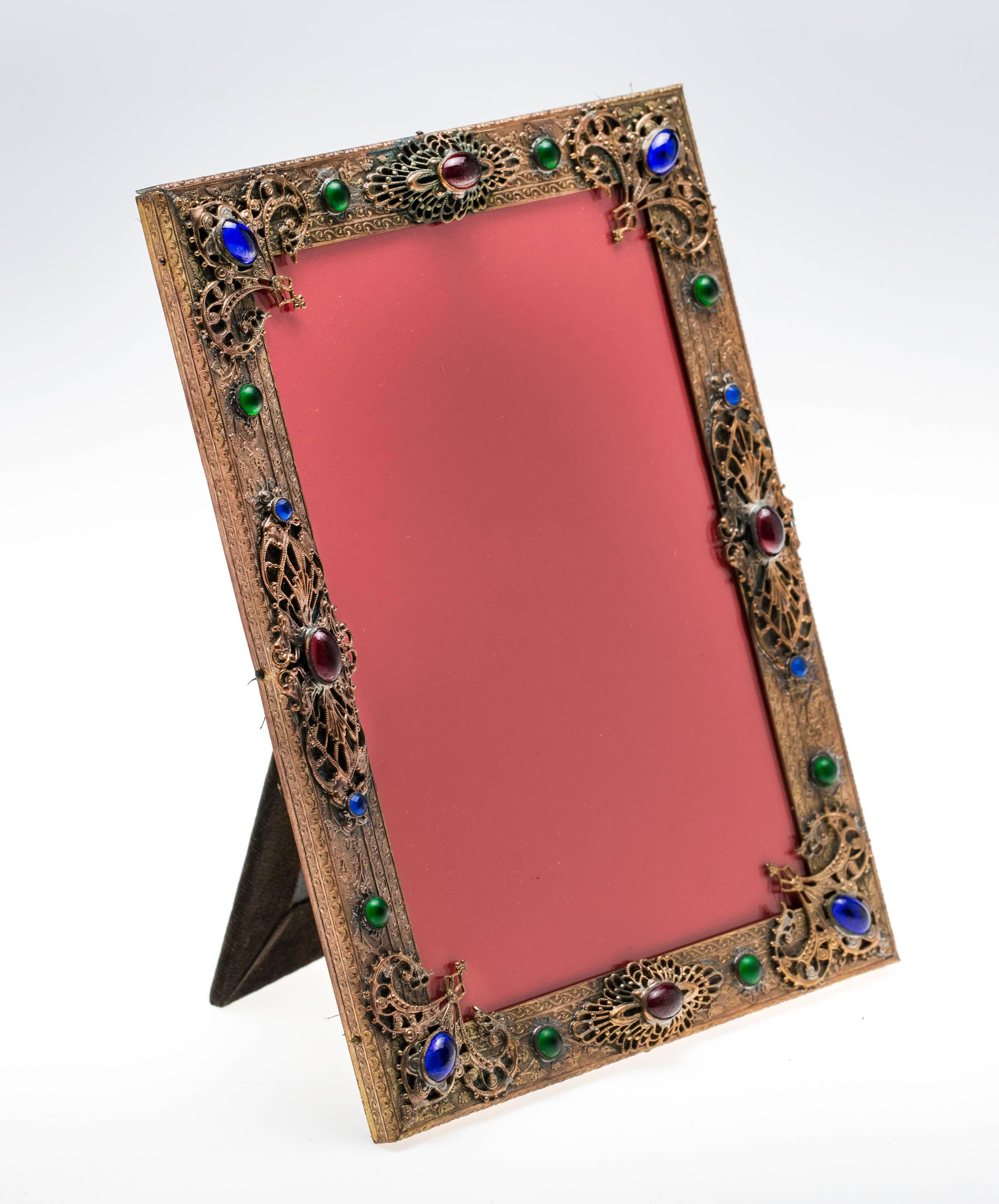 Bejeweled decoratively with green, blue and amber glass cabochons over gilt bronze filigree picture frame. Great for 5 x 7 photo picture.