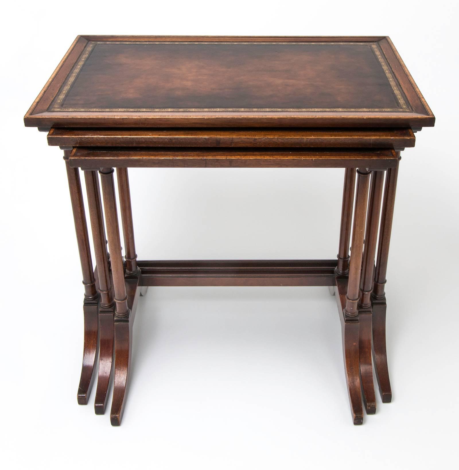 1920s, refined George III style mahogany nesting tables. Beautiful inset leather top tooled trim in 23-karat gold. Columnar legs, supported by shaped sledge feet. Practical and handy addition to your room. Measures: Large 24 x 15 x 24, medium 21 x