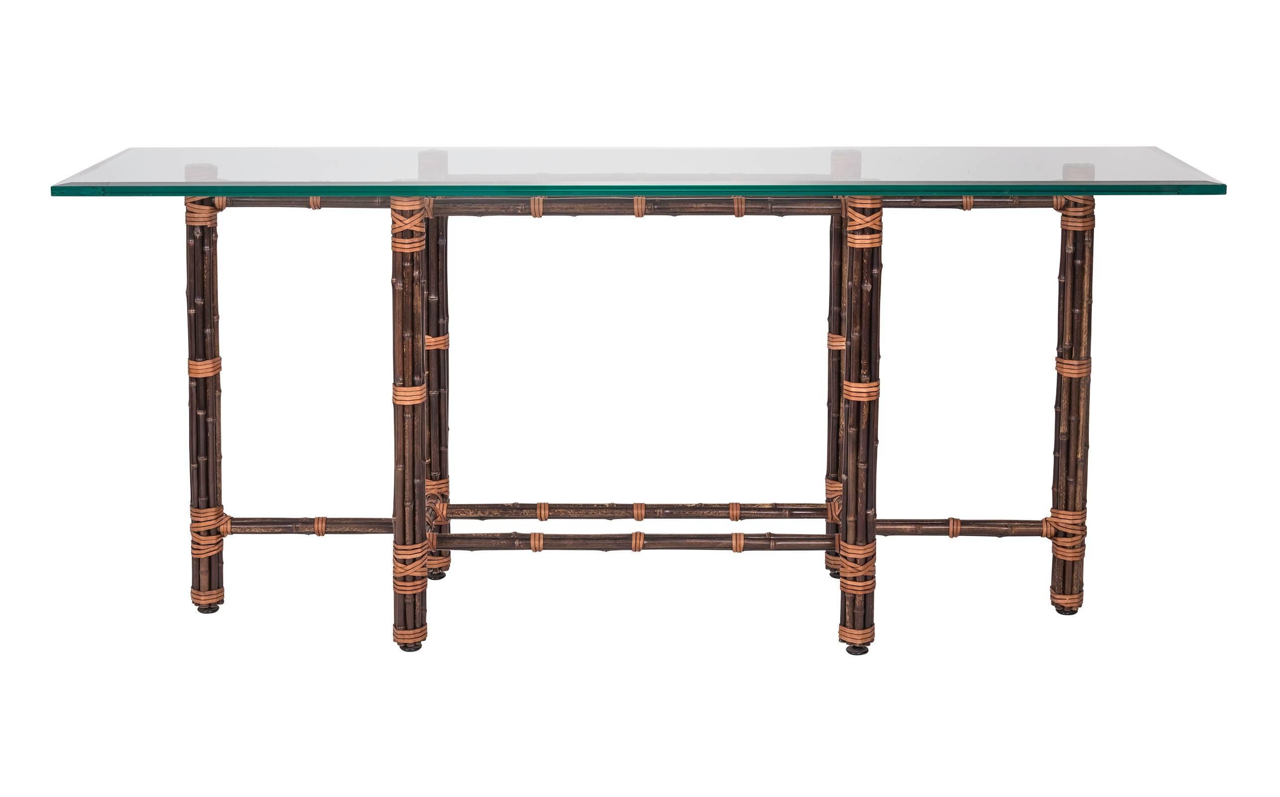 As always, quality well made McGuire bamboo sofa table. It can also be used as a serving table. Base is dark bamboo wrapped with contrasting leather straps. The top is 3/4" thick bevel glass. Very nice but there are few scratches on the glass.