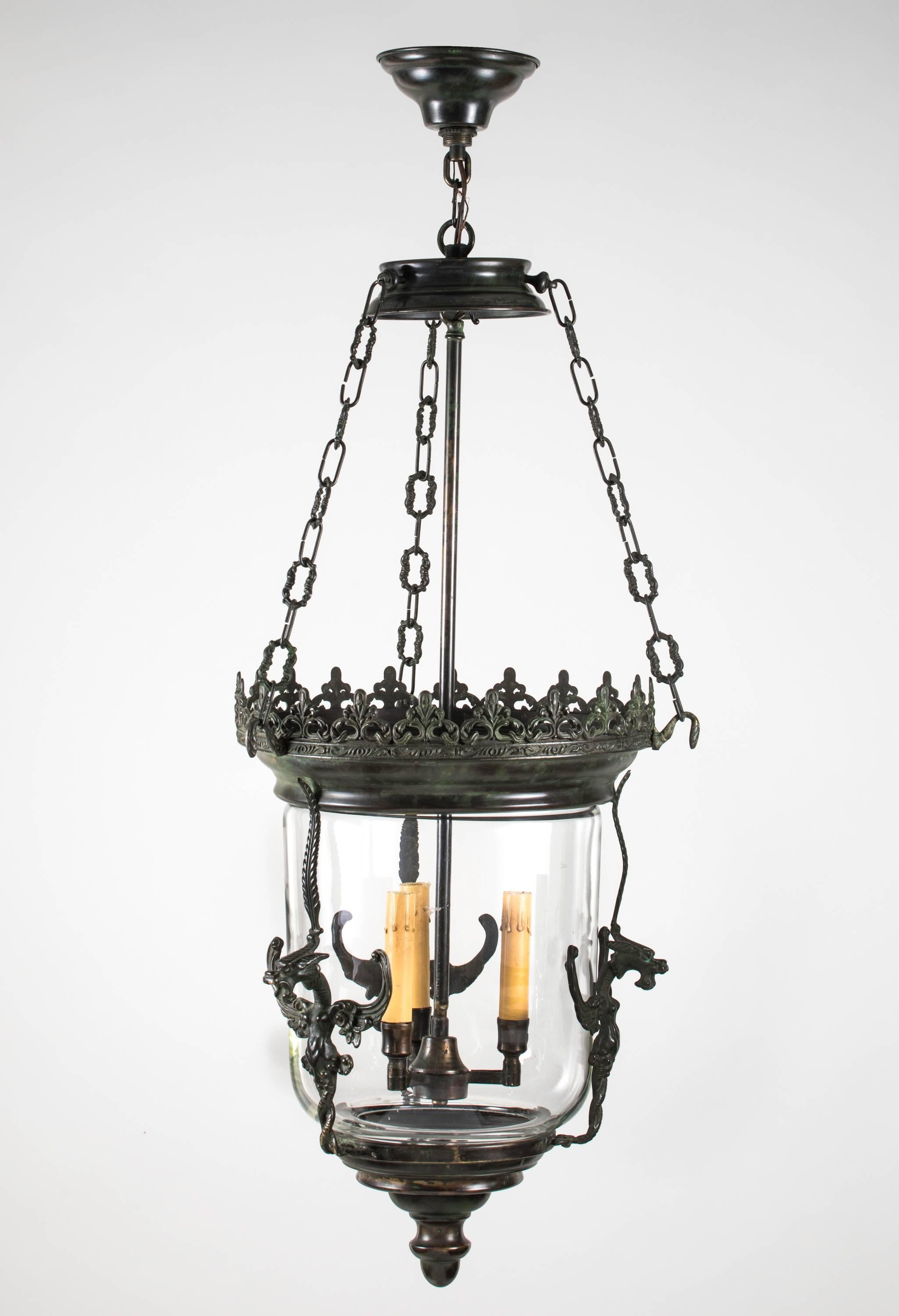 Decorative three-light glass lantern is surrounded in cast bronze frame flanked with three griffins. Beautiful crown work finishes the top. Lantern itself is 15 x 20. Great for entry or hallway lighting.