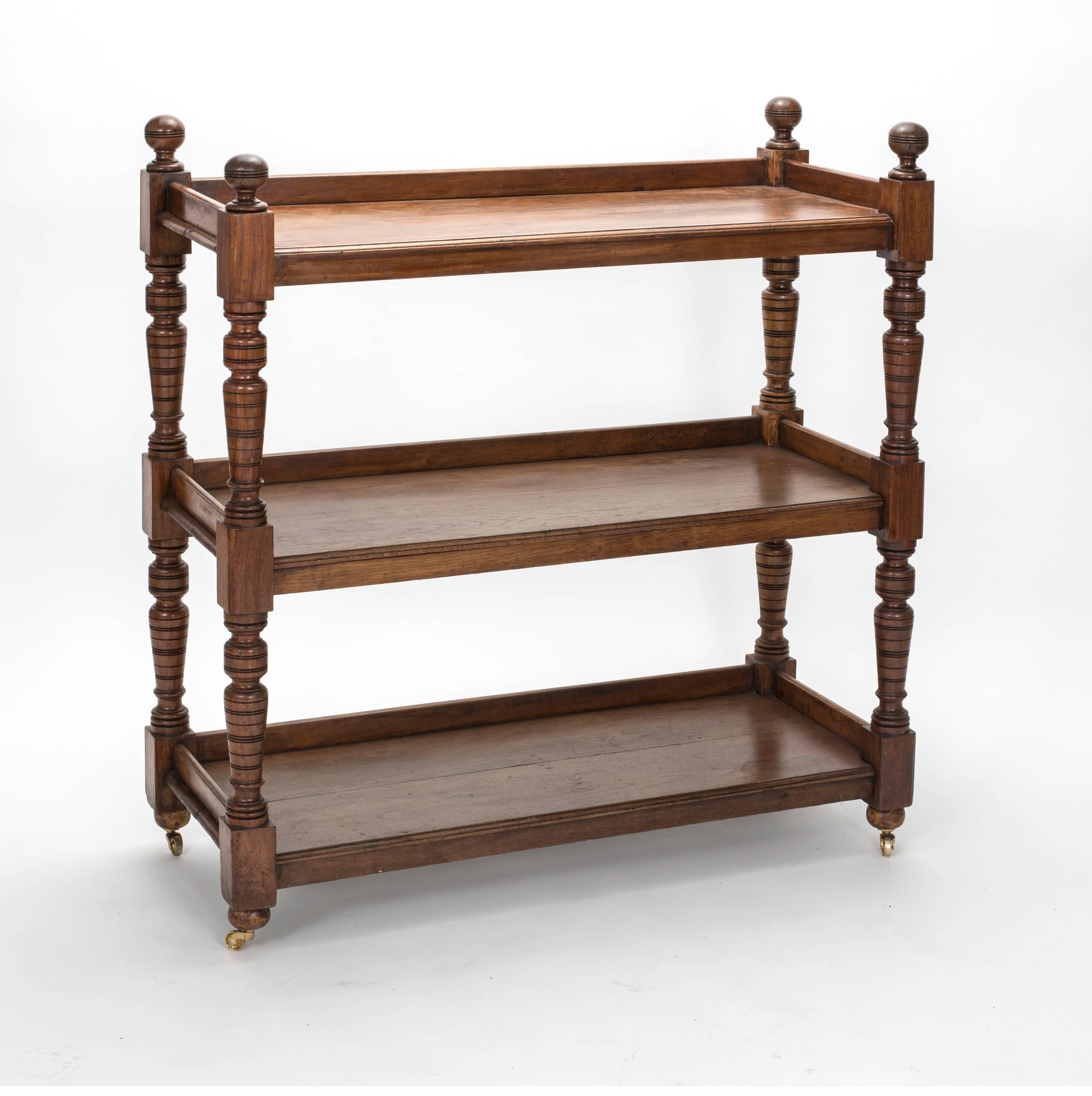 C. 1890s, Beautiful old English walnut wood trolley serving cart. Three-tier shelving for serving and displaying dining accessories. It is on brass castors for easy movement.