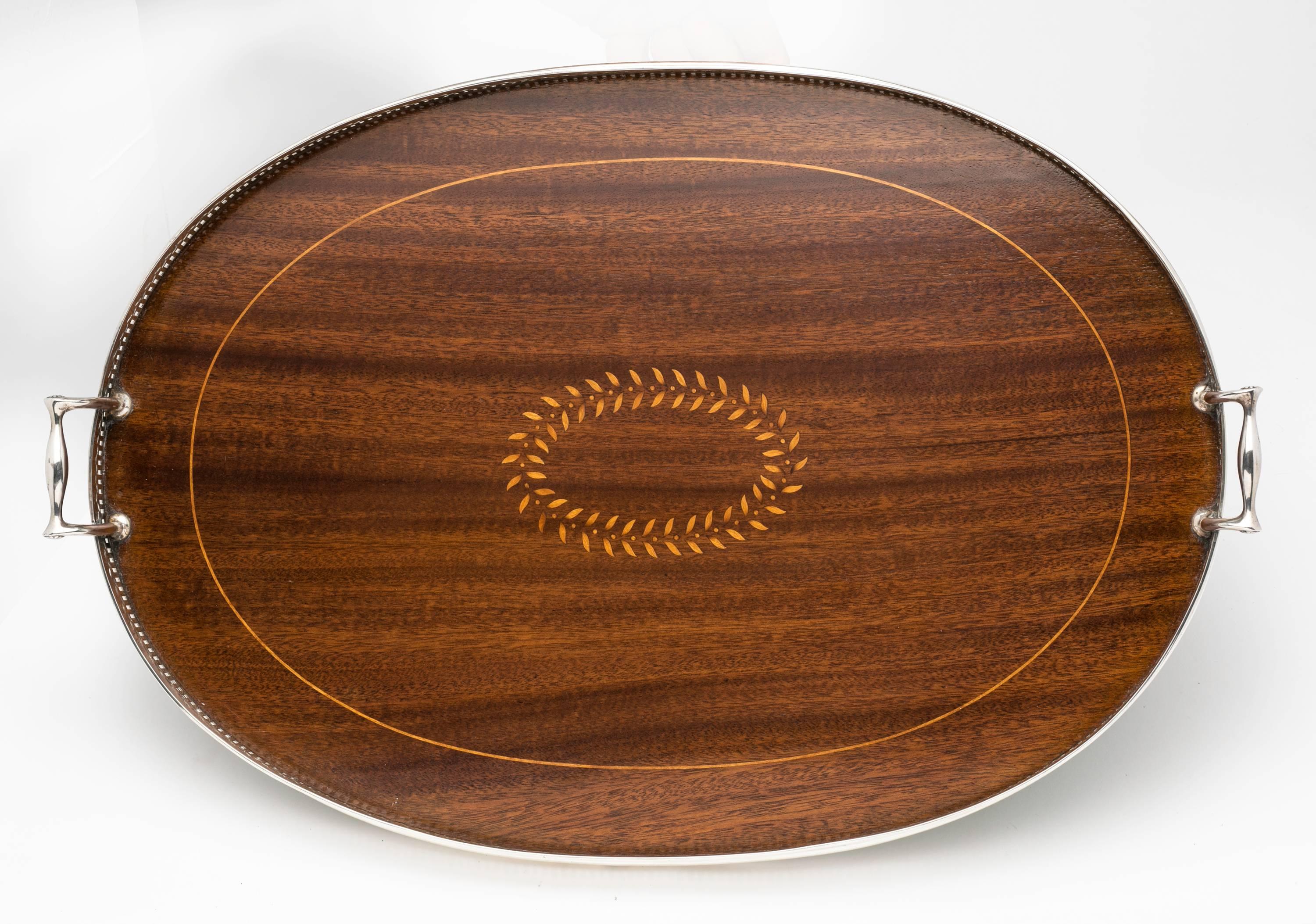 From 1920s, large oval Sterling silver tray with handles by Tiffany & Co. Mahogany wood with Satin wood inlaid marquetry in leaf design. Beval glass liner to protect the wood. Wonderful gallery tray server. (There is a small chipping at the edge of