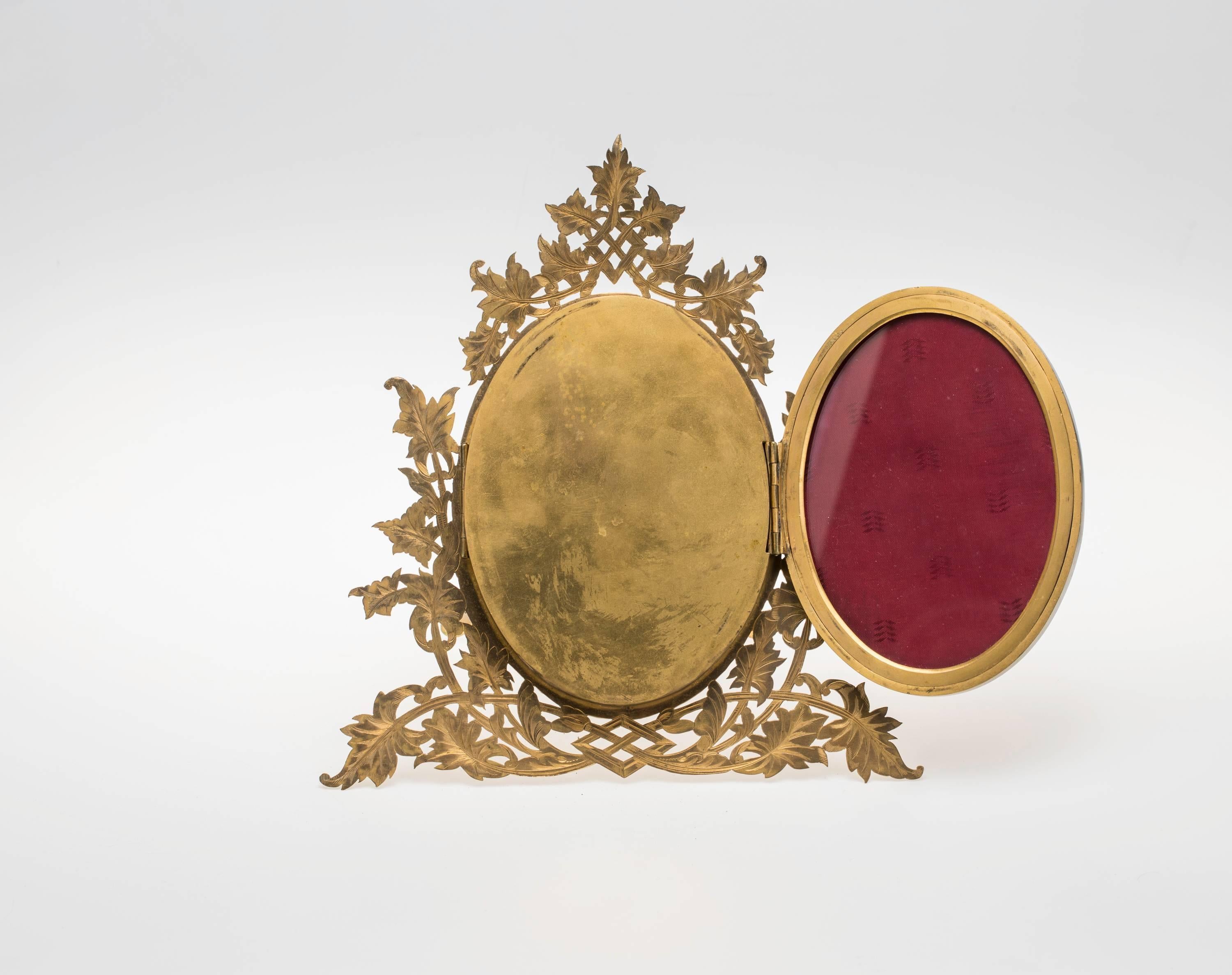 English gilt bronze triple oval folding picture frames, circa 1870. The two ovals flanks the main middle one which is adorned with beautiful pierced bronze design. The back panel is decoratively set with seven round agate stones. It its on hinged