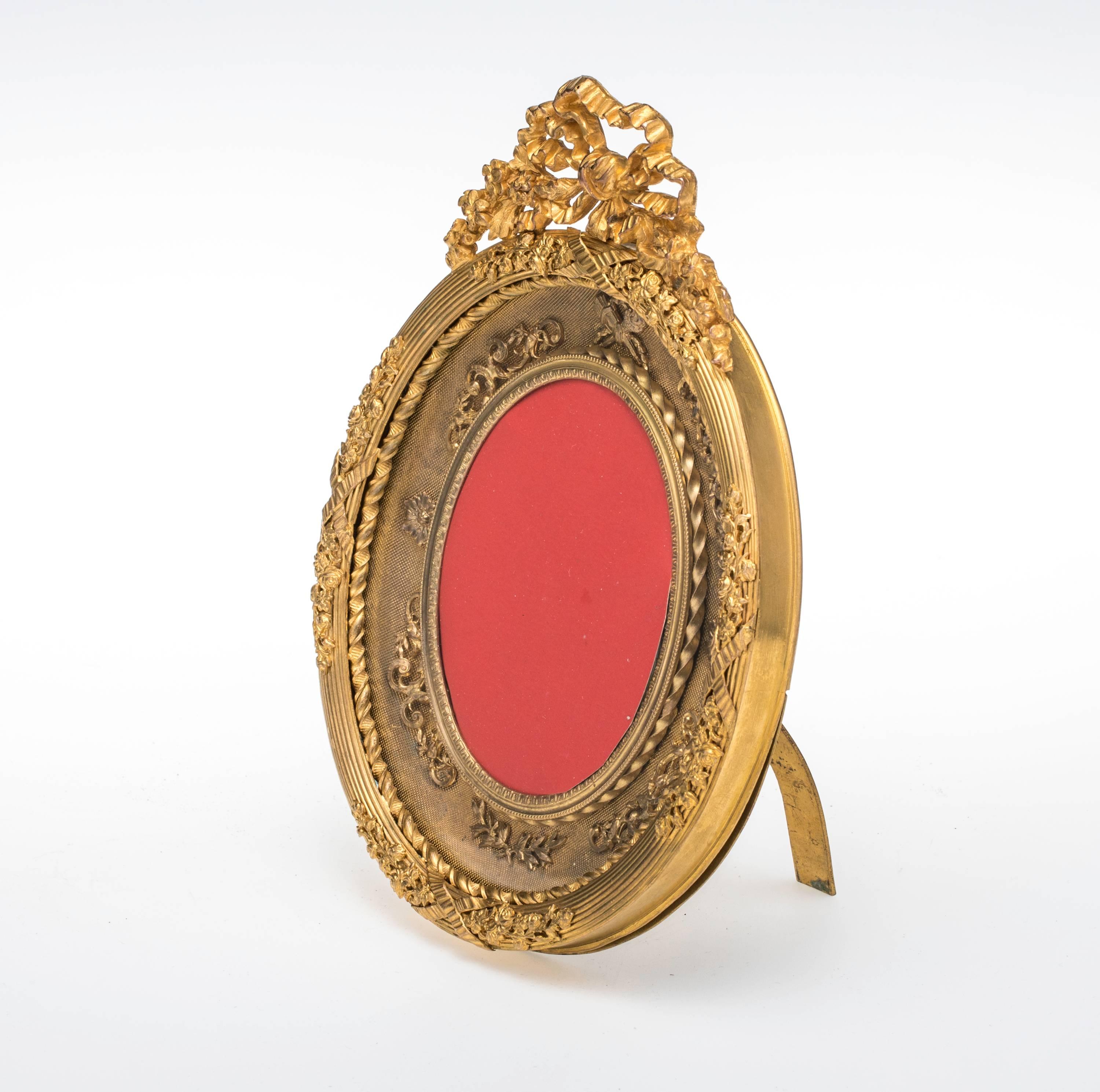 French gilt bronze Dore  oval picture frame, circa 1880s. Superbly cast detailed with ribbon flowers motif. Back panel is held with turning screw. It sits properly with folding easel stand.