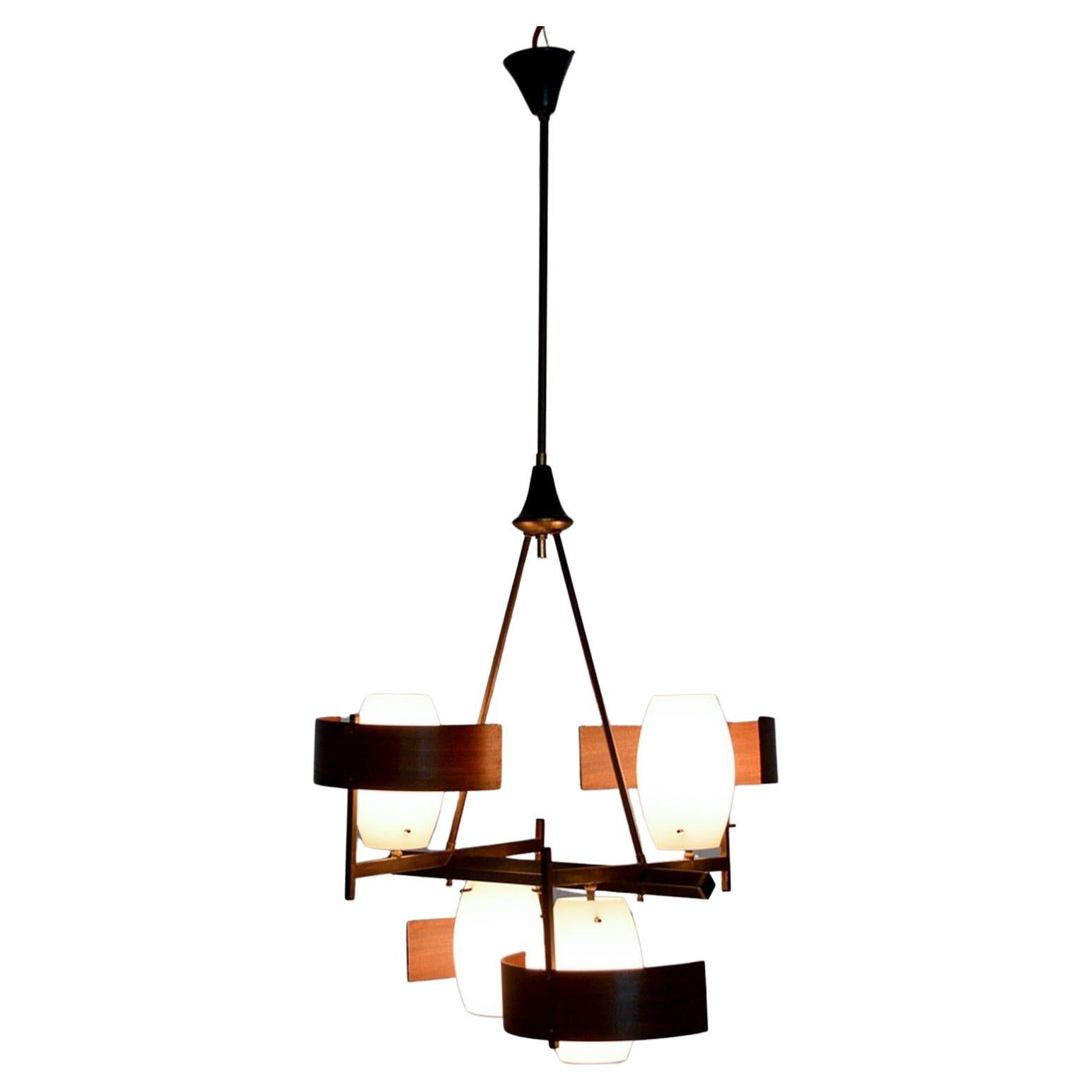 Vintage Italian chandelier patinated brass, sapele bent plywood diffusers and opaline glass shades. 
Aluminum canopies painted in black.
H 41 in. x W 15 in. x D 19 in.
Unmarked. Chandelier requires four E-14 bulbs. Not included. 
Restored, aluminum