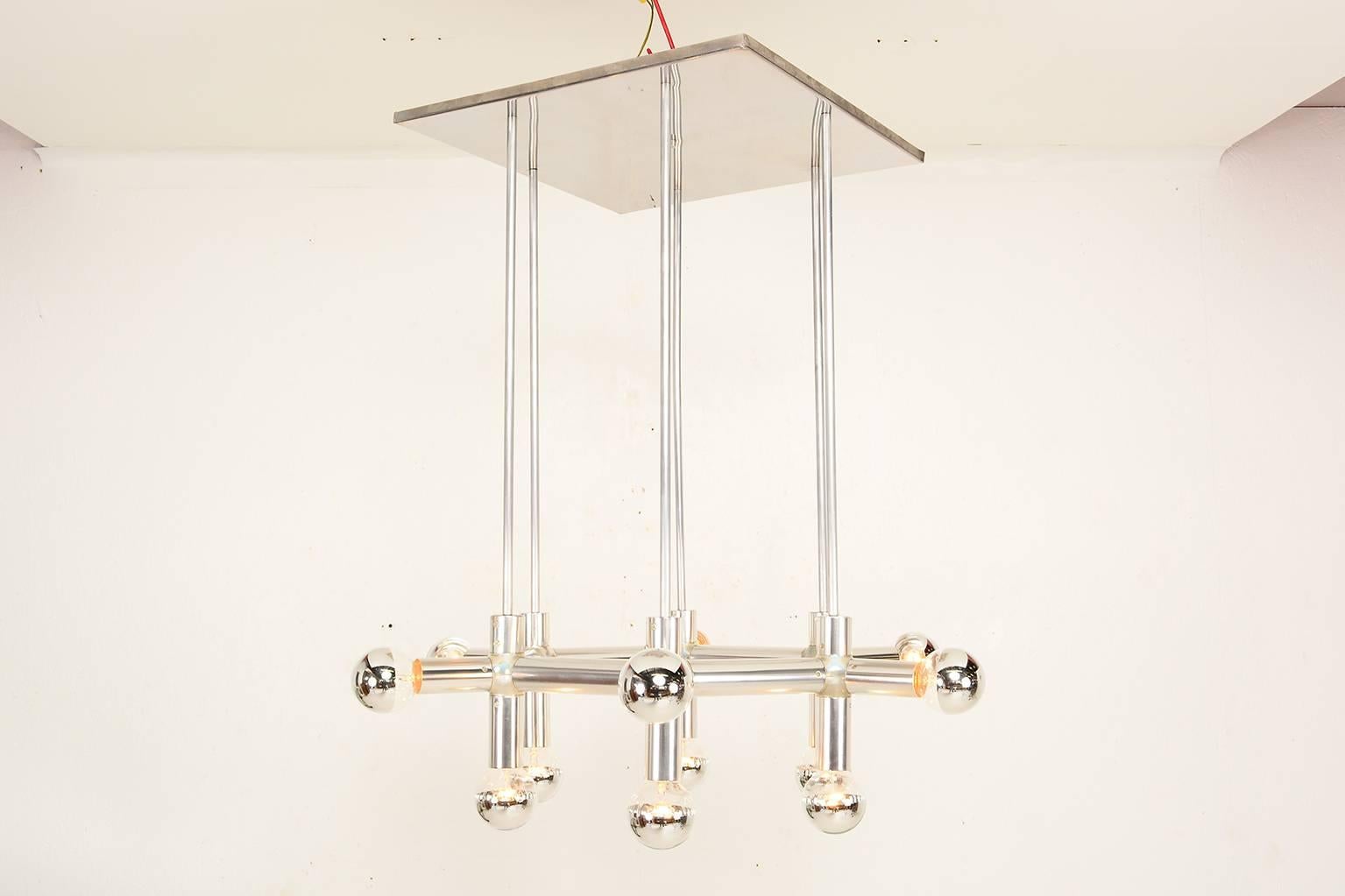 For your consideration a vintage chandelier by Robert Haussmann. 

Atomic/molecular in anodized aluminum.

Requires 12 bulb (included 25 watts half chrome round shape).

The chandelier is suspended by aluminum rods from a stainless steel