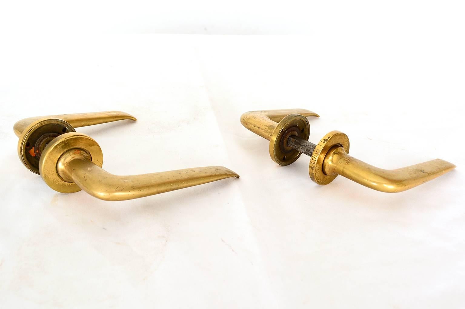For your consideration a pair of solid brass door handles in sculptural shape.

Beautiful design with clean modern lines.
The clever design secures the handle into the frame of the door with three screws. The screws are concealed with a brass