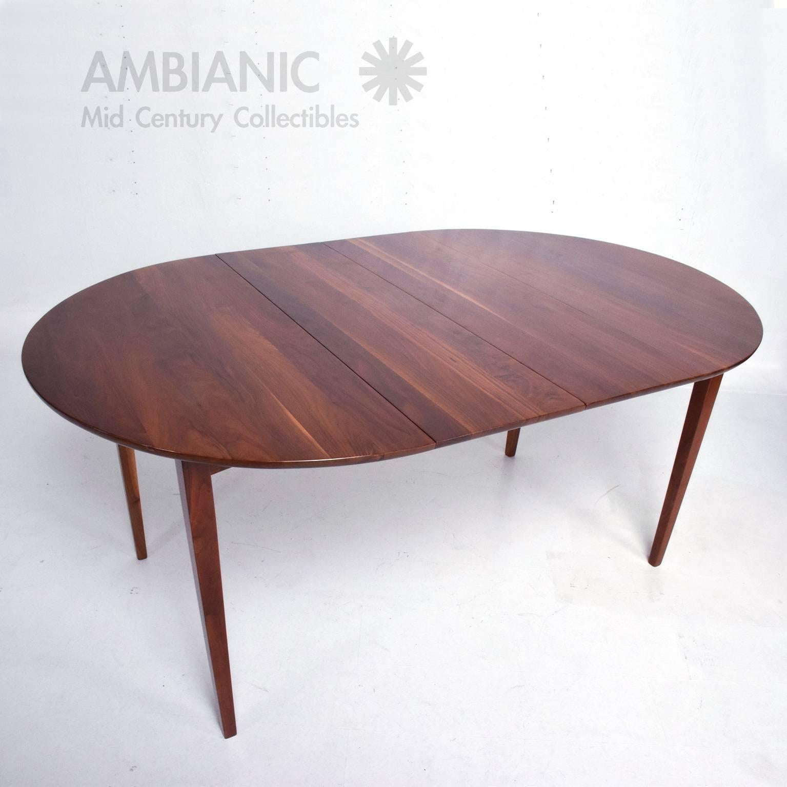 For your consideration a solid walnut wood dining table in round shape with two extensions (forms an oval shape).

USA, circa 1960s.

Legs can be removed for safe and easy shipping. 

Measures: 42