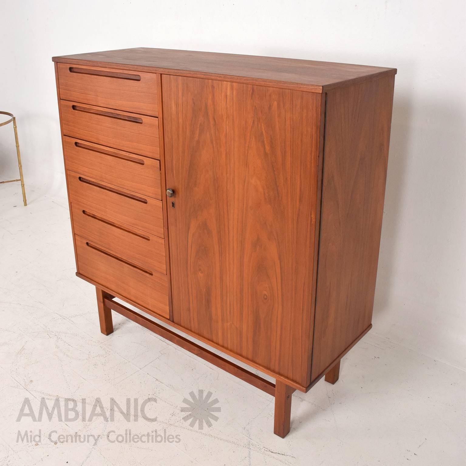 For your consideration a tall highboy in teak wood by Nils Jonsson. Clean modern lines with sculptural pull handles. All drawers open and close with ease and are constructed with double dove tail joints. 

The right side has a door which cover