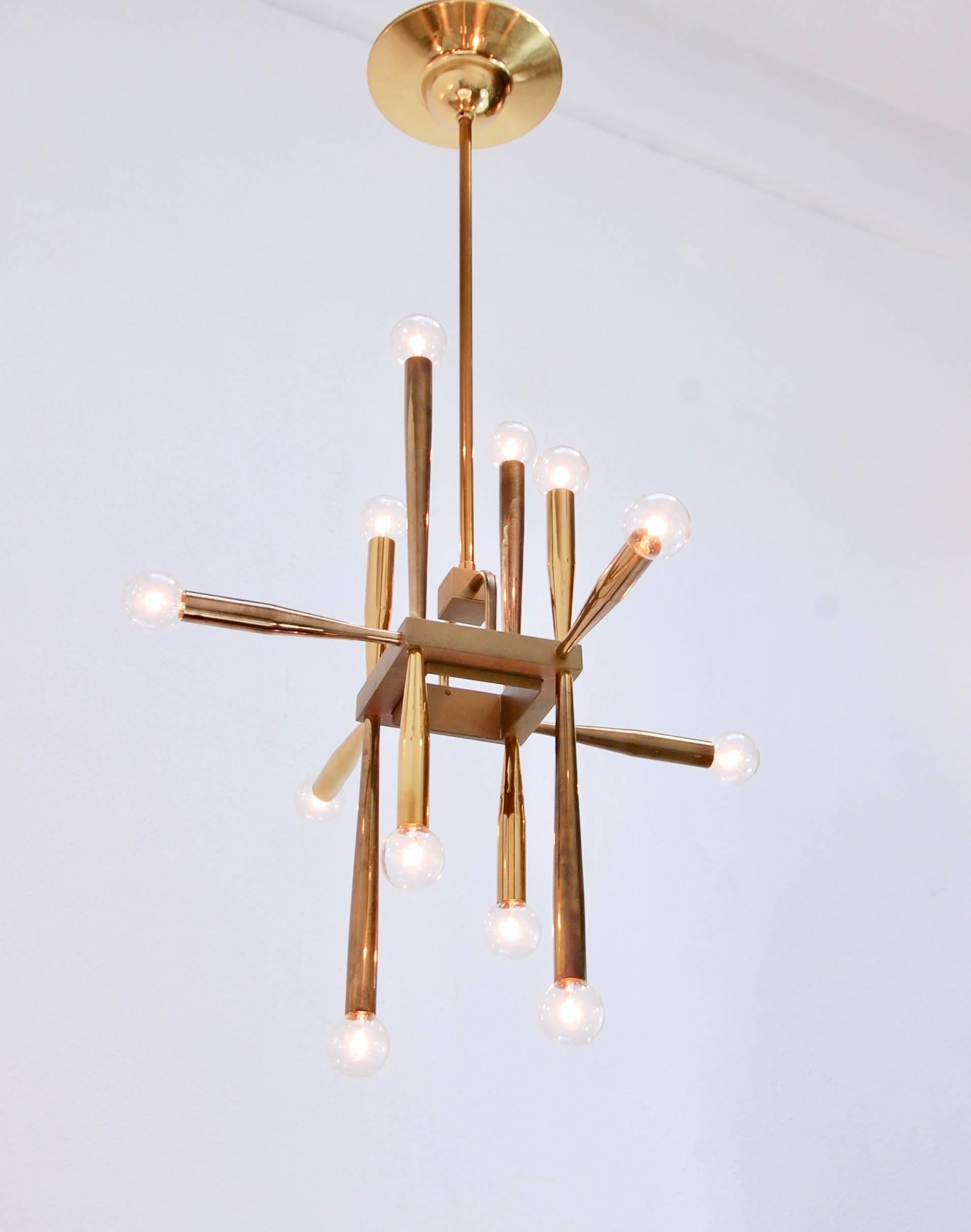 Of the period 12 light cubic Mid-Century Modern chandelier from Italy. Partially restored, original patinated brass finish, 12 individual E12 candelabra based sockets per arm, wired for the US. Overall drop adjustable upon request. Measures: Overall
